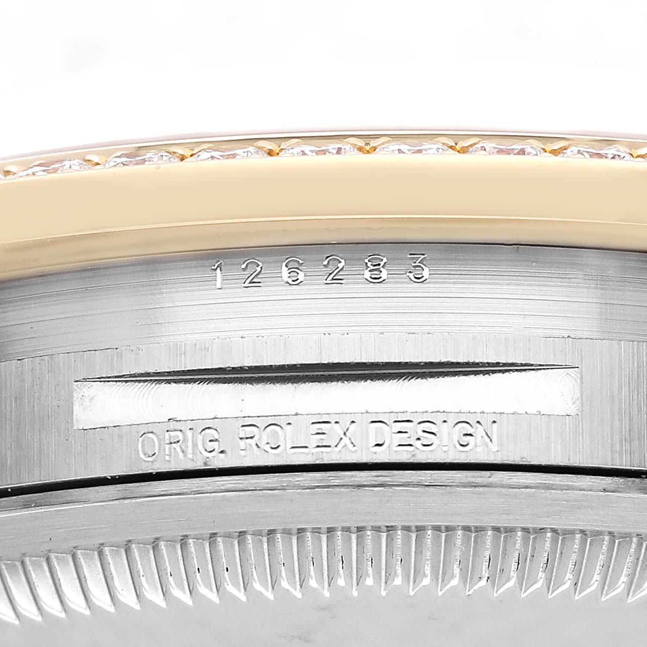 The image shows a close-up side view of a Rolex Datejust 126283RBR Men's Steel and Gold (two tone) Champagne Dial watch, focusing on the bezel and engraved design details.
