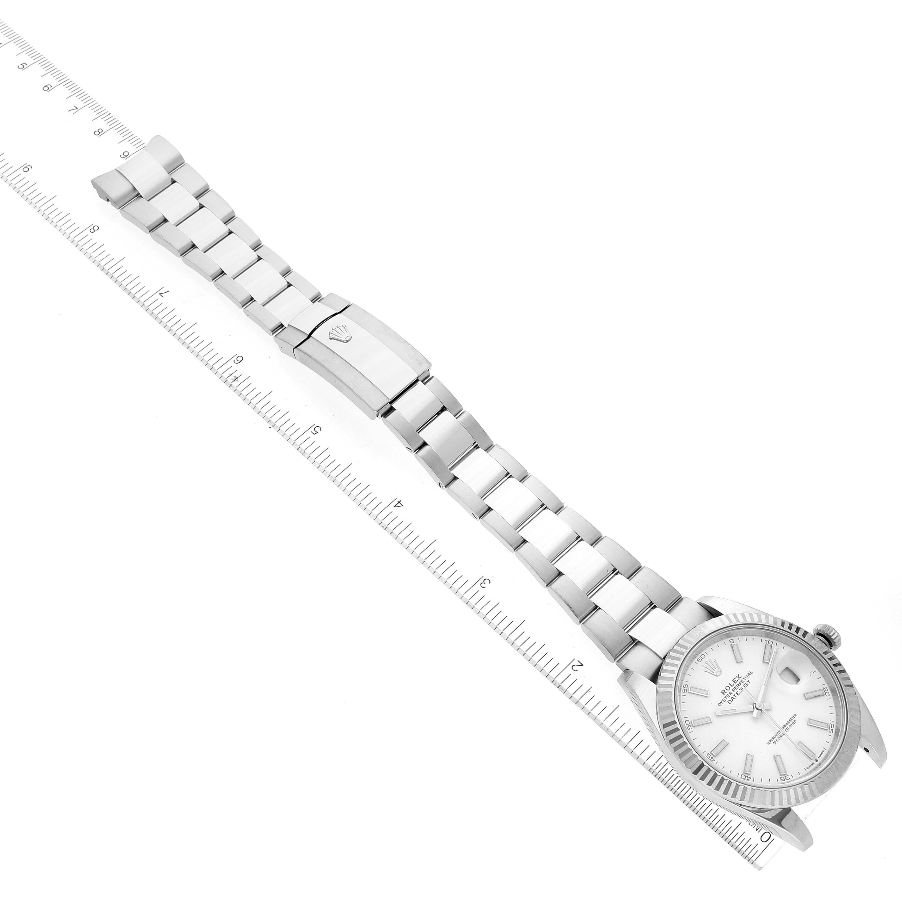 The image shows a top view of the Rolex Datejust 41 126334 Men's Stainless Steel White Dial 126334 Men's Stainless Steel White Dial model, highlighting the watch face and metal bracelet alongside a ruler for scale.