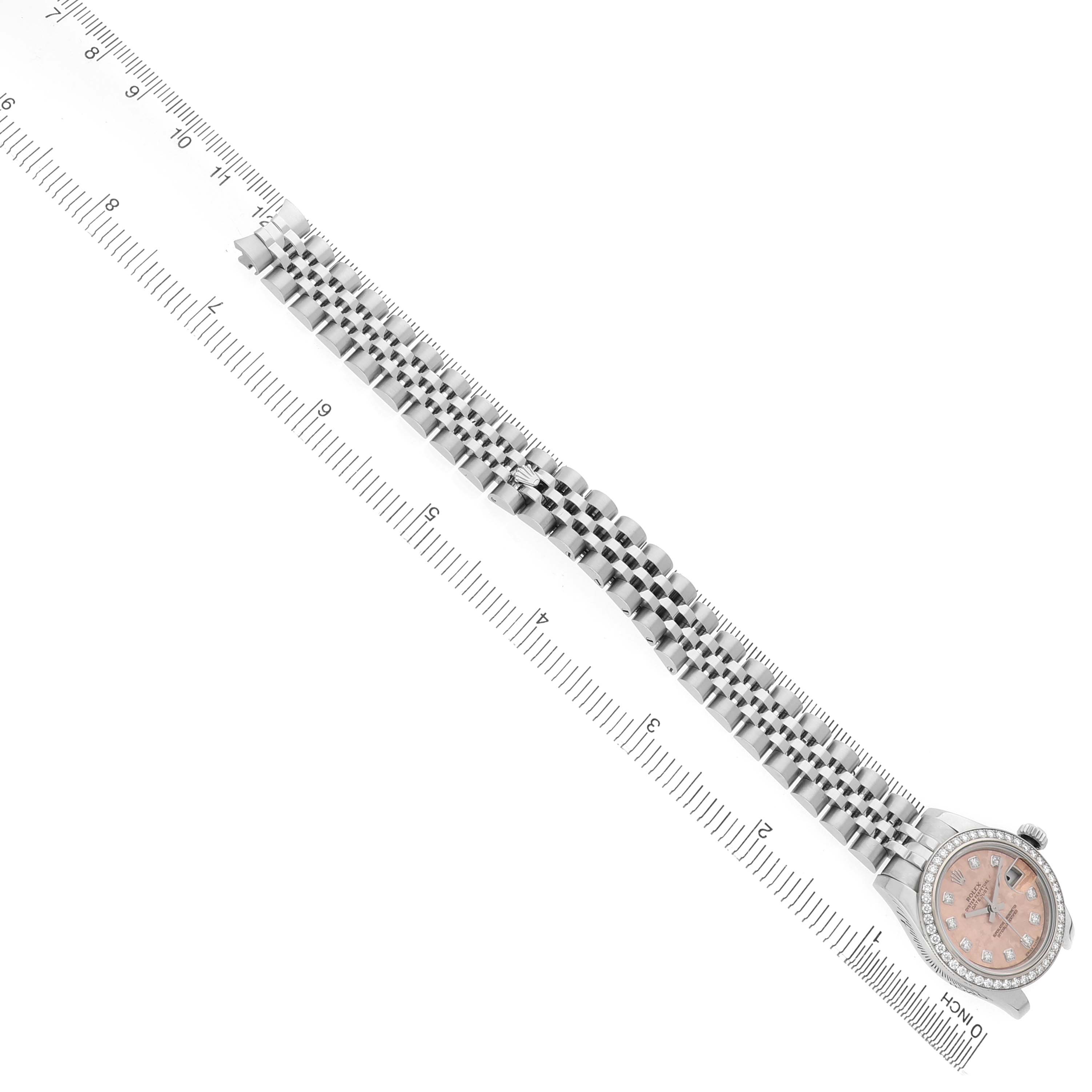 The Rolex Datejust 179384 Women's Stainless Steel Pink Dial watch is shown at an angled top view, displaying the face and full bracelet length alongside a ruler.