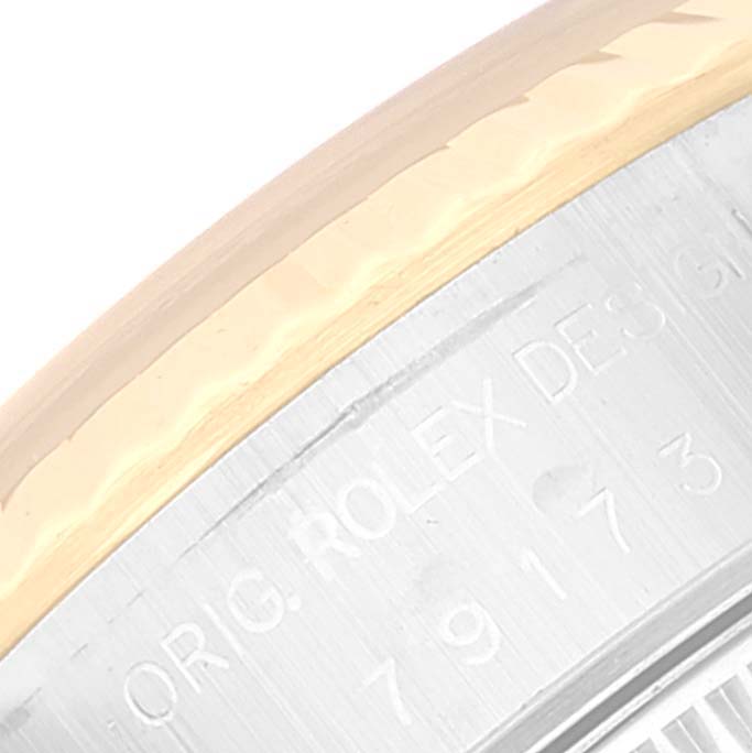 This image shows a close-up of the side of a Rolex Datejust 79173 Women's Steel and Gold (two tone) Black Dial 79173 Women's Steel and Gold (two tone) Black Dial model case, highlighting engraved text and part of the bezel.