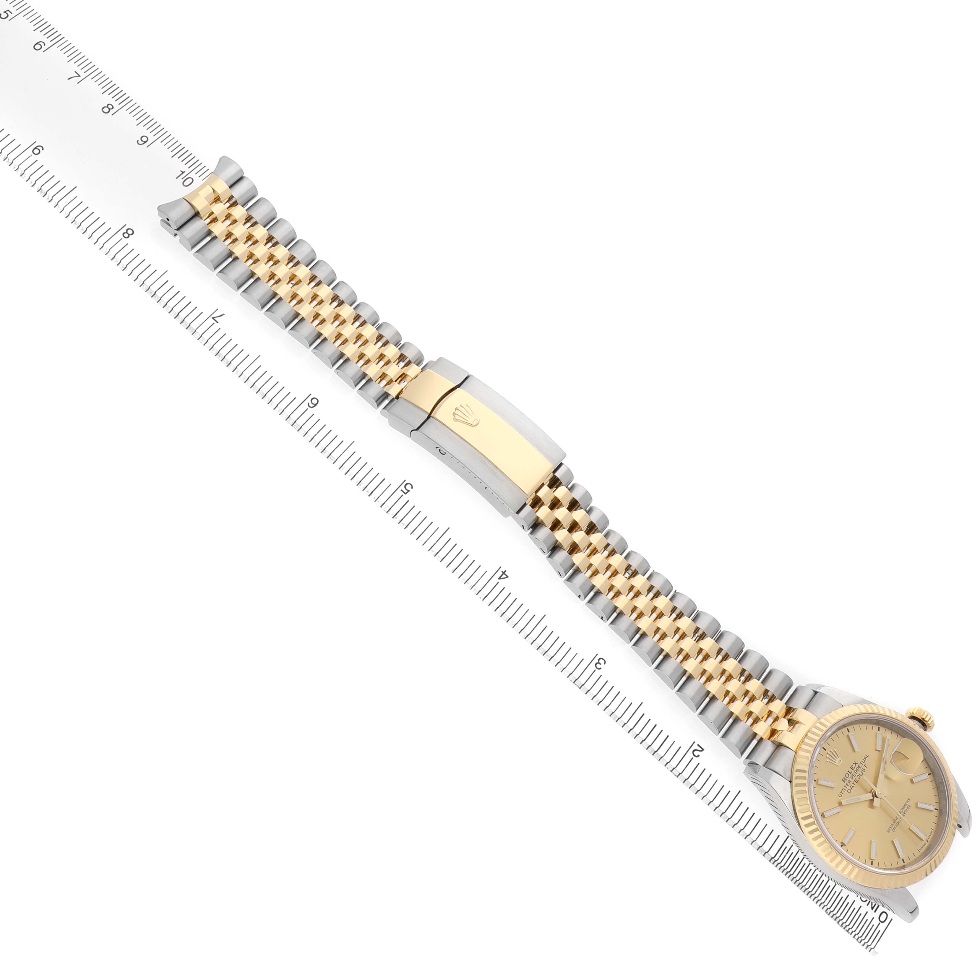 The image shows a Rolex Datejust 126233 Men's Steel and Gold (two tone) Champagne Dial watch at an angled view, highlighting the bracelet, clasp, and watch face next to a ruler.