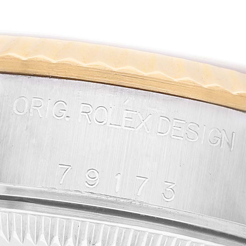 The image shows a close-up of the side of a Rolex Datejust 79173 Women's Stainless Steel Silver Dial watch, featuring the engraved model number and "ORIG. ROLEX DESIGN."
