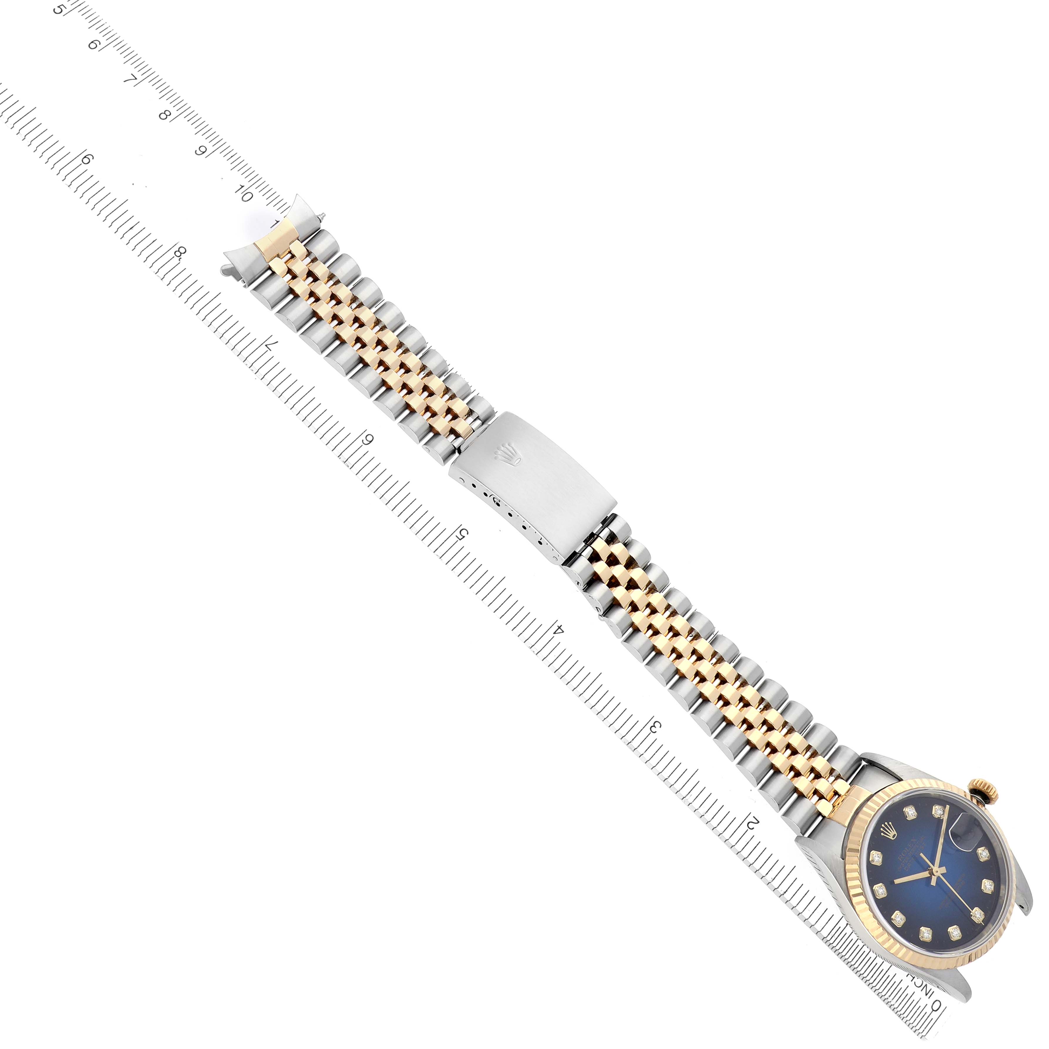 The Rolex Datejust 16233 Men's Steel and Gold (two tone) Blue Dial 16233 Men's Steel and Gold (two tone) Blue Dial watch is shown from a top-down angle with its bracelet fully extended alongside a ruler for scale.