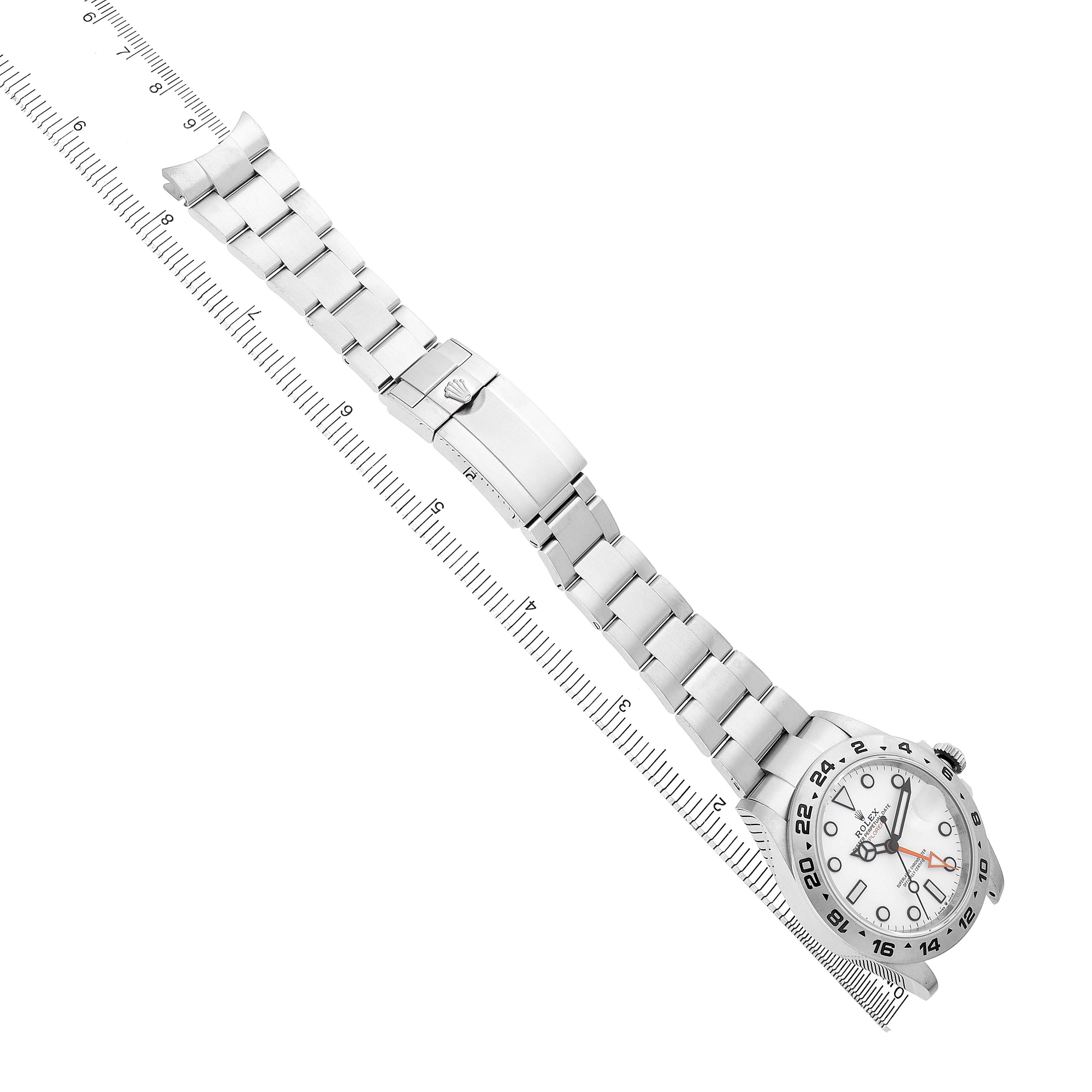 The Rolex Explorer 226570 Men's Stainless Steel White Dial watch is shown from an angled side view, highlighting the face, bracelet, and clasp with a measuring ruler.