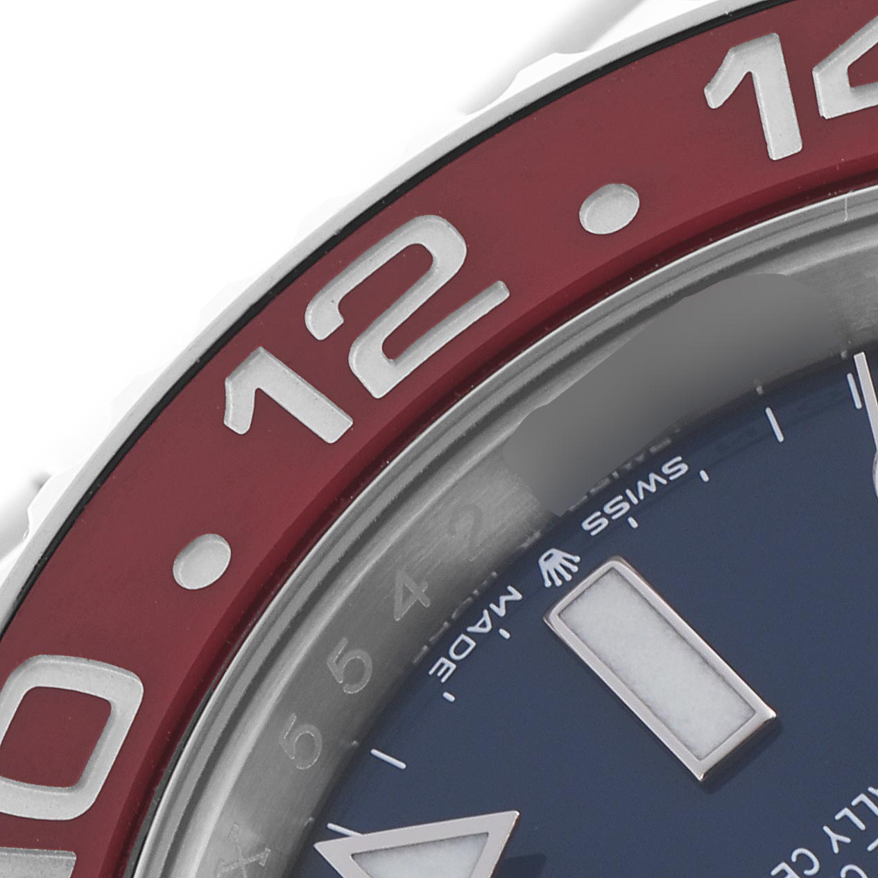 The image shows a close-up of the bezel and part of the dial of a Rolex GMT-Master 126719 Men's White Gold Blue Dial 126719 Men's White Gold Blue Dial, featuring the "12" marker and deep red color.