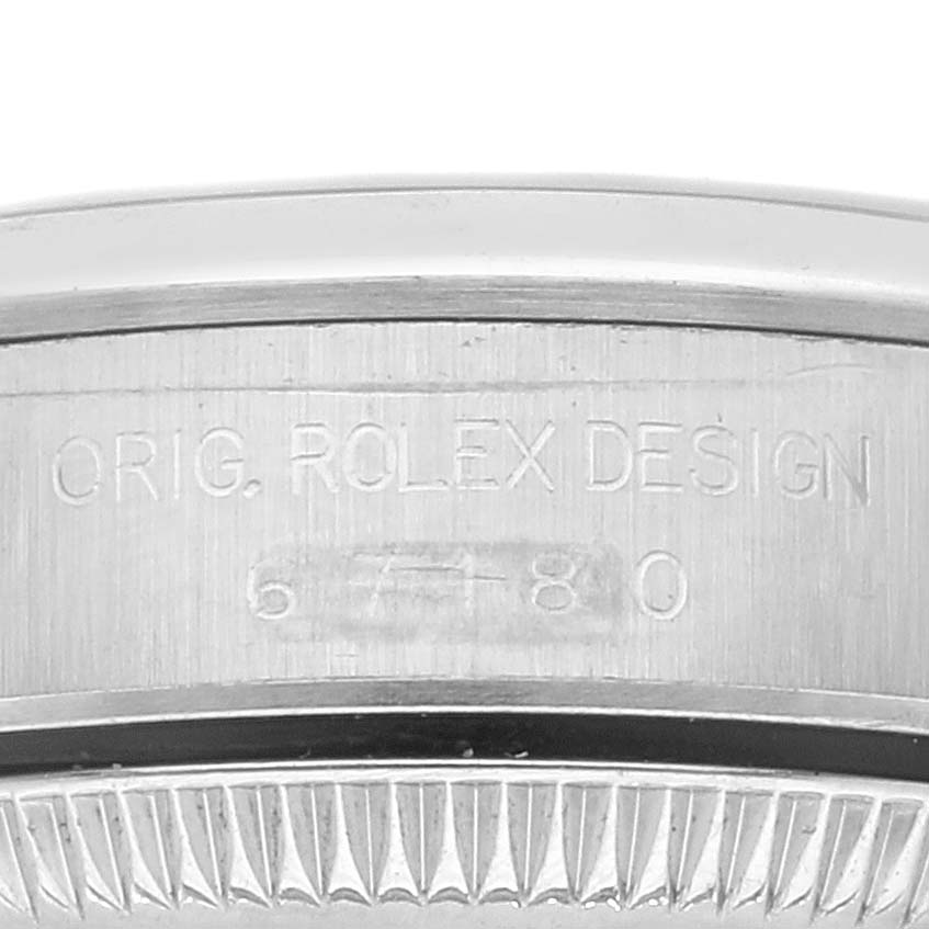 This image shows the engraved side of the bezel from a Rolex Oyster Perpetual 67180 Women's Stainless Steel Blue Dial 67180 Women's Stainless Steel Blue Dial watch, displaying "Orig. Rolex Design" and a reference number.