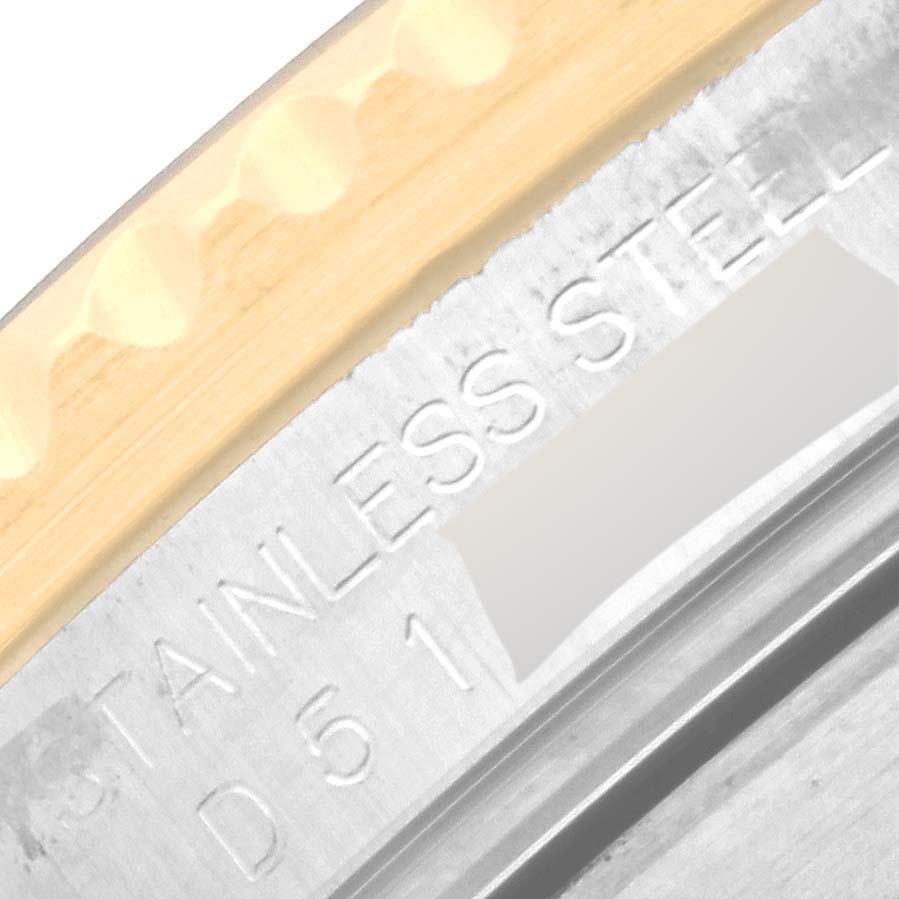 The image shows an extreme close-up of a Rolex Submariner 16613LB Men's Steel and Gold (two tone) Champagne Dial 16613LB Men's Steel and Gold (two tone) Champagne Dial's case edge with "STAINLESS STEEL" engraved.