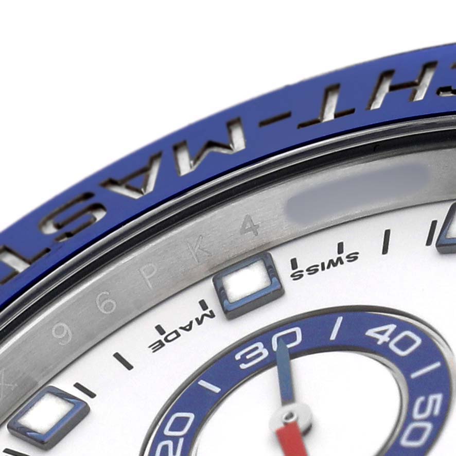 The image shows a close-up of the bezel and part of the dial of a Rolex Yacht-Master 116680 Men's Stainless Steel White Dial watch, highlighting its blue and silver detailing.