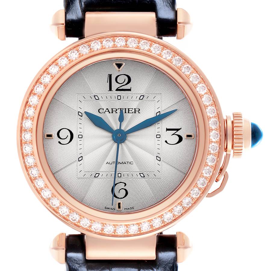 The Cartier Pasha watch is shown from the front, highlighting its face, bezel with diamonds, blue hands, and crown with a blue gemstone.