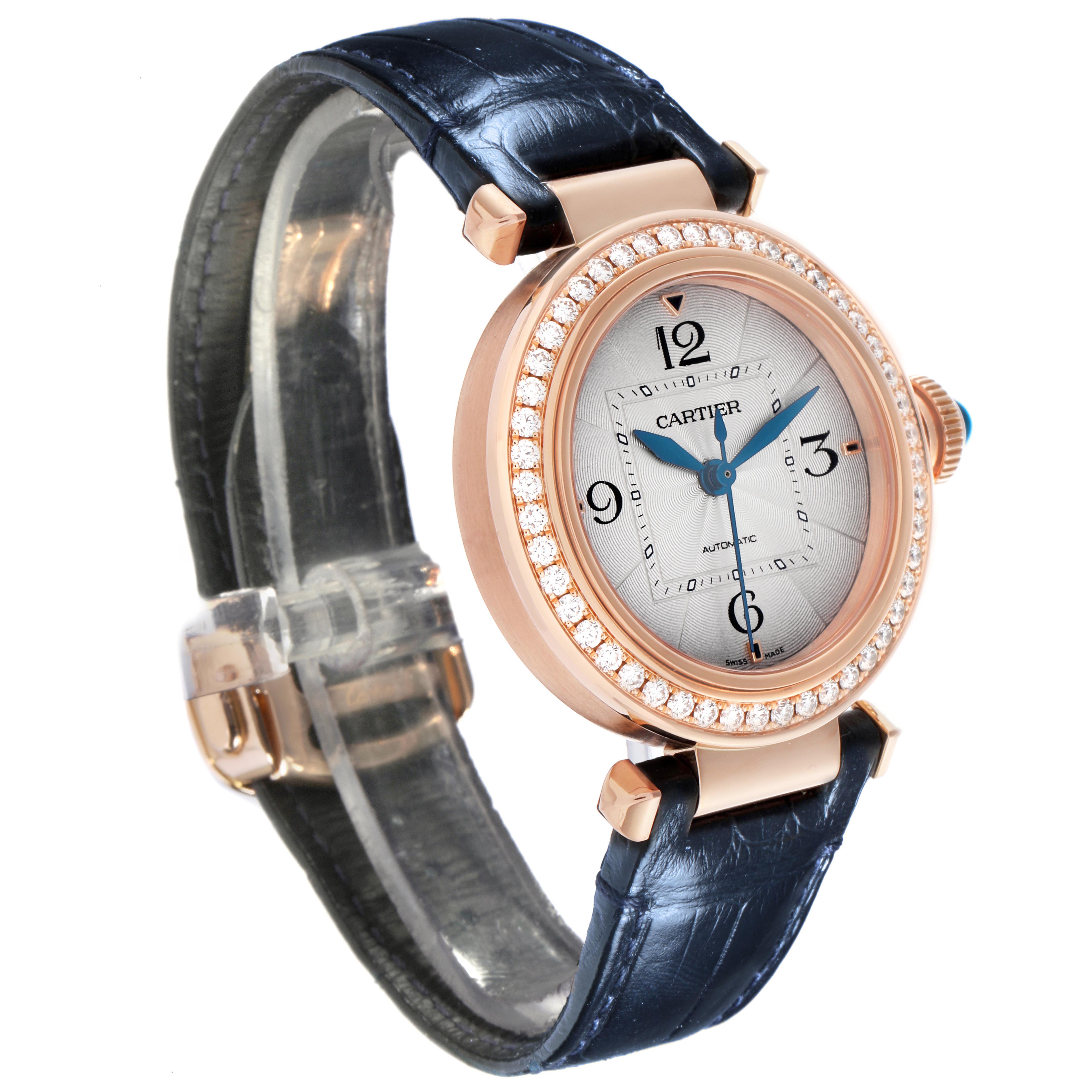 The Cartier Pasha WJPA0012 Women's Rose Gold Silver Dial watch is shown in a three-quarter angle, highlighting its diamond bezel, dial, and blue leather strap.