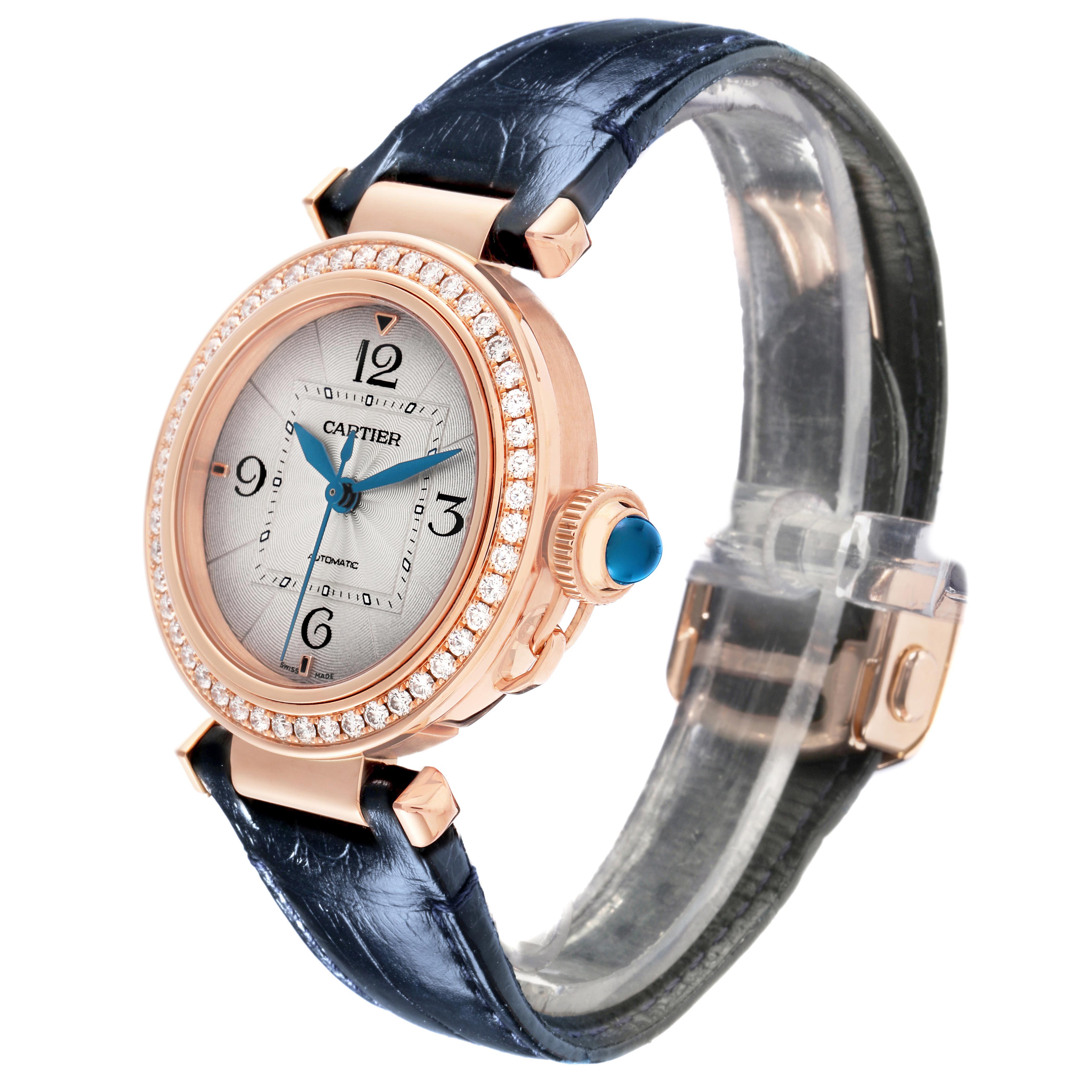 The Cartier Pasha WJPA0012 Women's Rose Gold Silver Dial watch is shown at a three-quarter angle, highlighting its dial, bezel with diamonds, and blue strap.