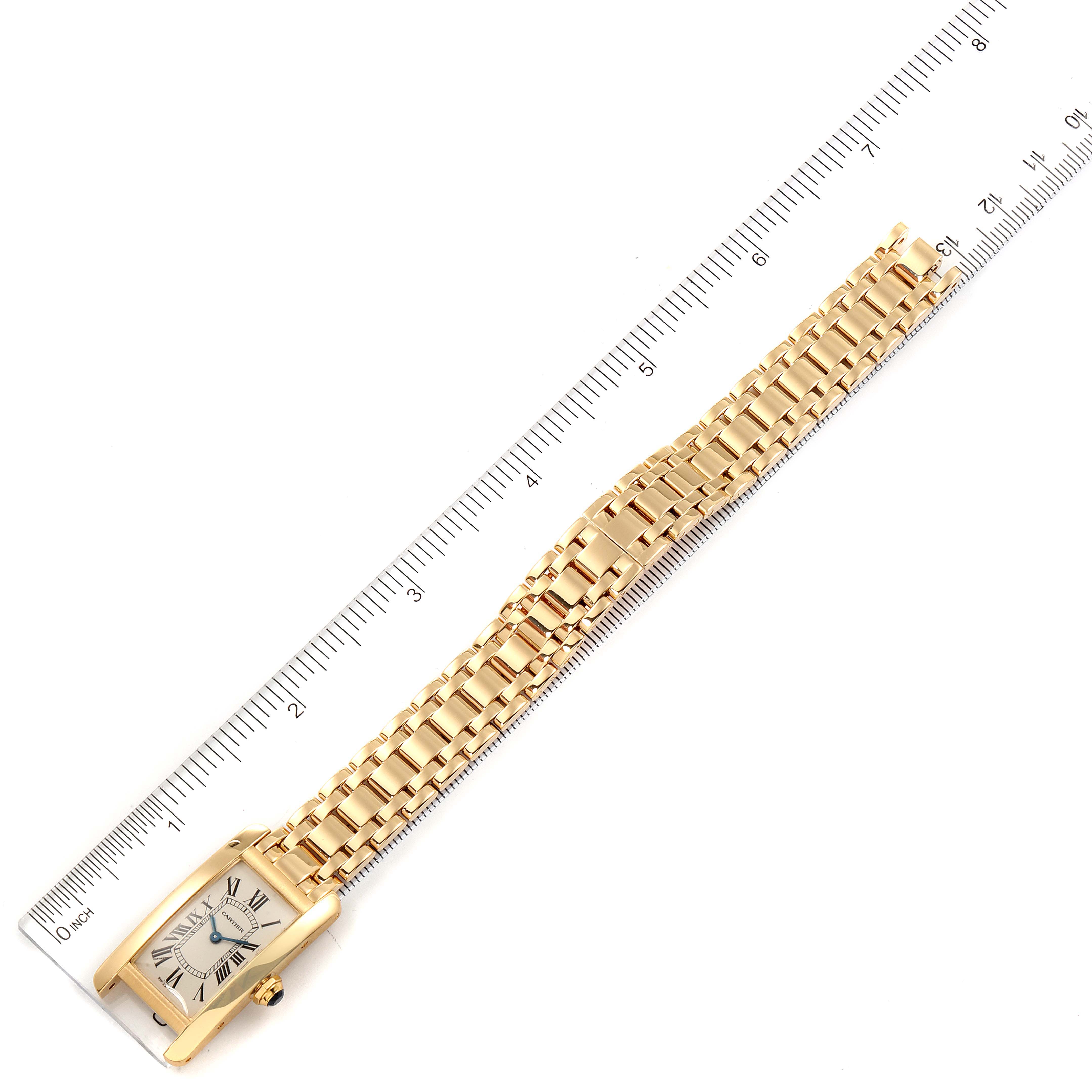 This image shows a Cartier Tank Americaine W26015K2 Women's Yellow Gold Silver Dial W26015K2 Women's Yellow Gold Silver Dial watch from a top-down angle, including its face, strap, and a ruler for size reference.