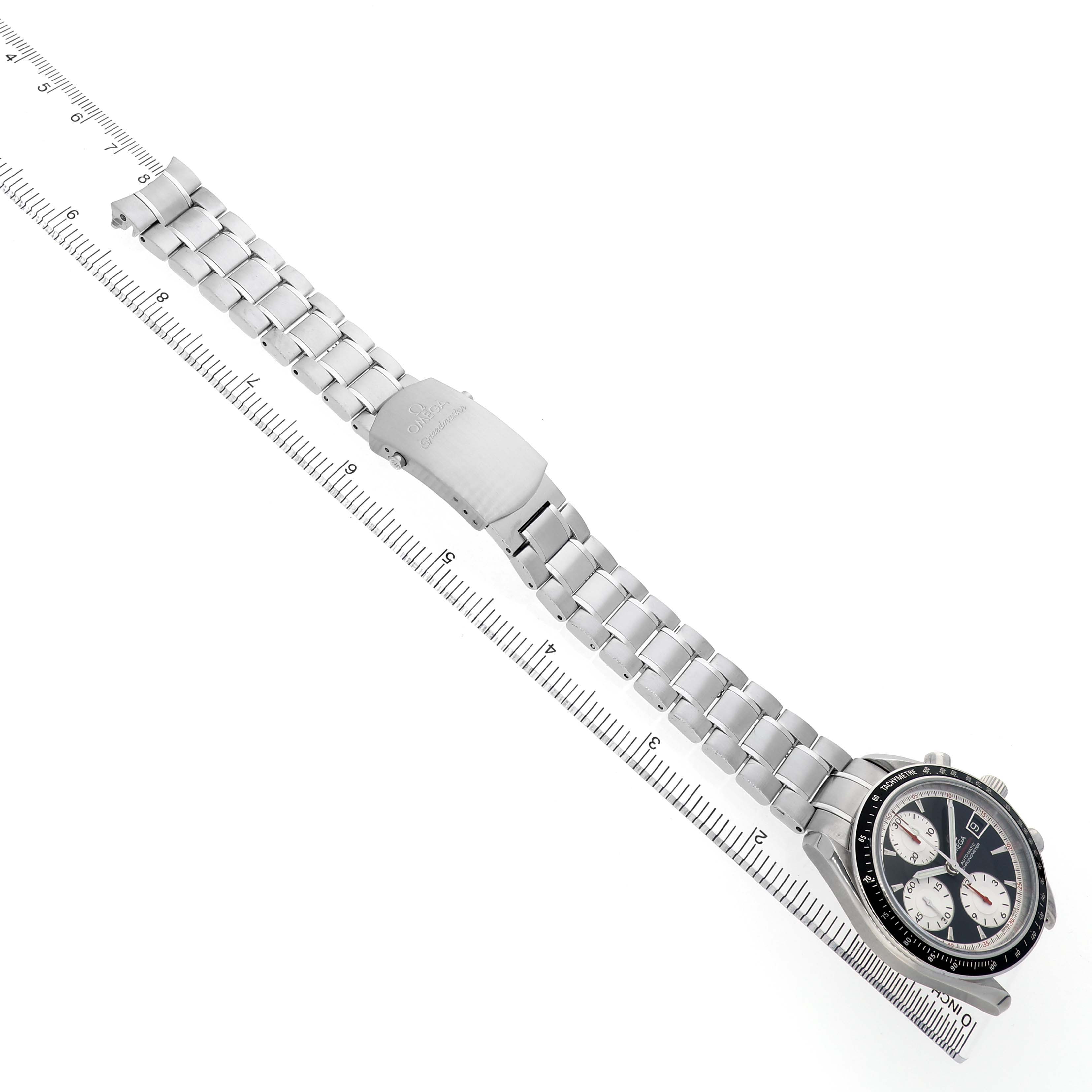 The Omega Speedmaster 3210.51.00 Men's Stainless Steel Black Dial watch is shown from a top angle, displaying its metal bracelet and face next to a ruler for scale.