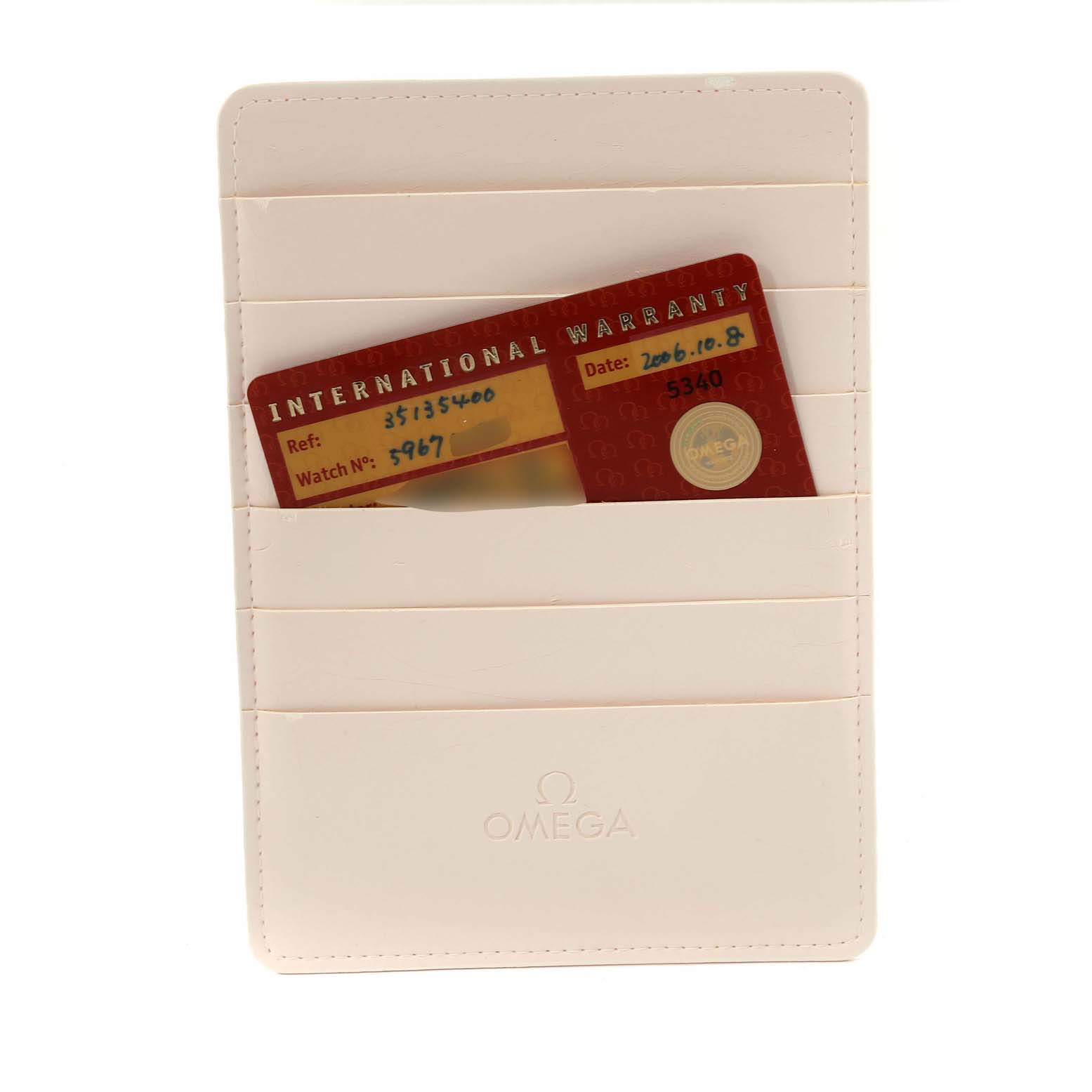 The image shows an Omega Speedmaster 3513.54.00 Men
s Stainless Steel Black Dial 3513.54.00 Men
s Stainless Steel Black Dial
s International Warranty card placed inside a cream-colored cardholder.