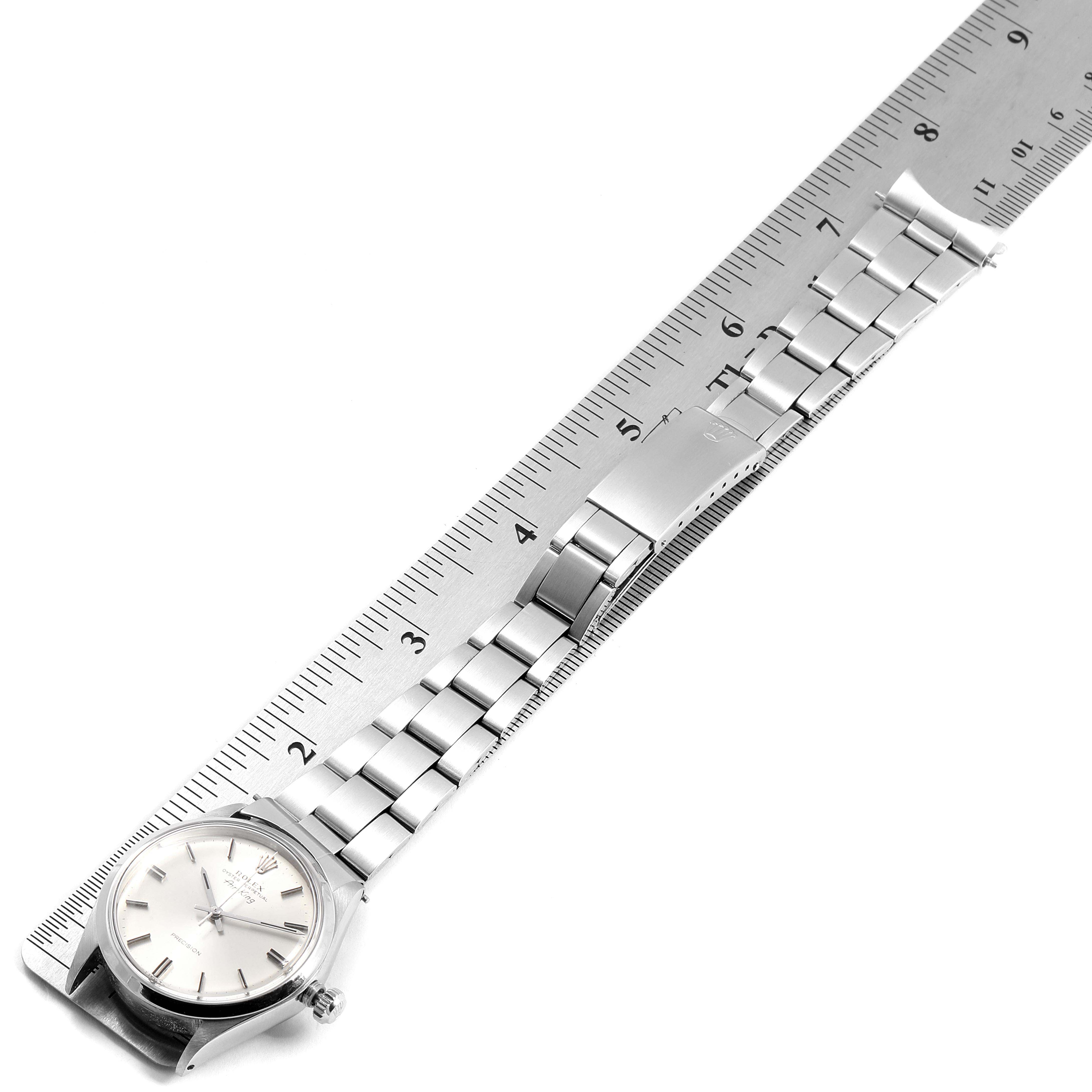 This image shows a Rolex Air-King 5500 Men's Stainless Steel Silver Dial 5500 Men's Stainless Steel Silver Dial watch laid flat against a ruler, showcasing its face, bracelet, and clasp.