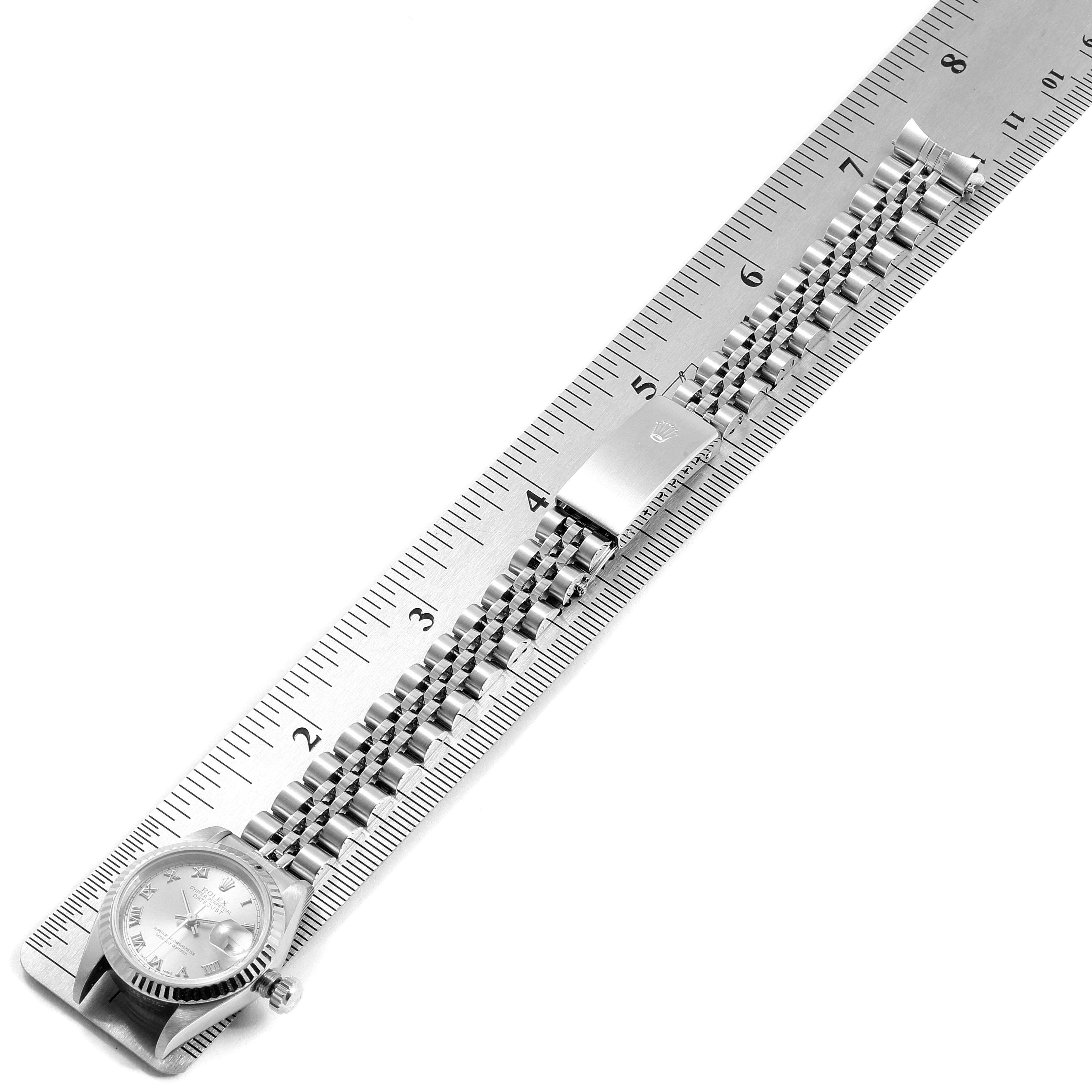 The image shows a Rolex Datejust 79174 Women
s Stainless Steel Silver Dial 79174 Women
s Stainless Steel Silver Dial watch laid flat on a ruler, displaying the face, crown, and bracelet.