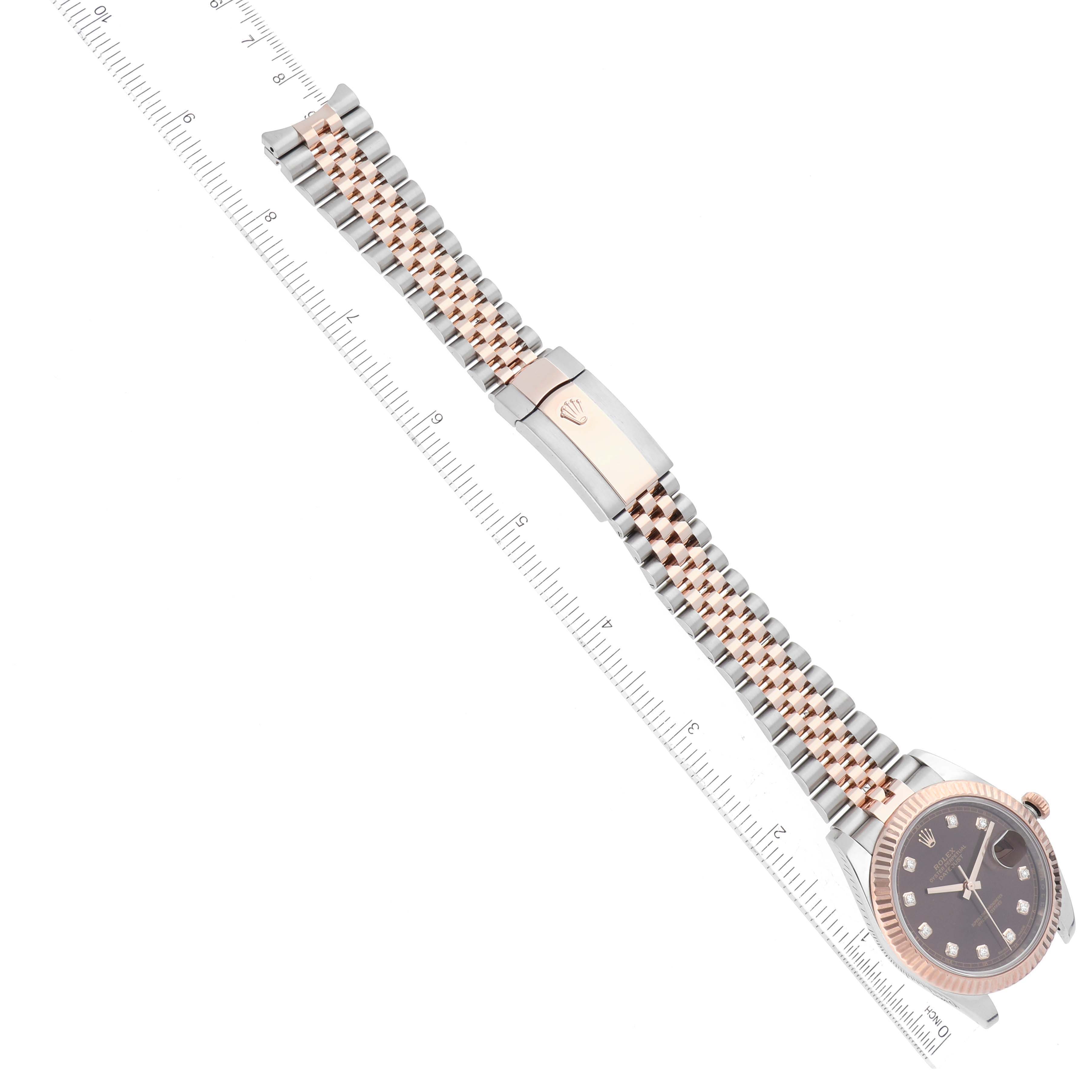 The image shows a Rolex Datejust 41 126331 Men
s Steel and Gold (two tone) Brown Dial 126331 Men
s Steel and Gold (two tone) Brown Dial watch laid flat, displaying its bracelet, clasp, and dial, with a ruler beside it for scale.