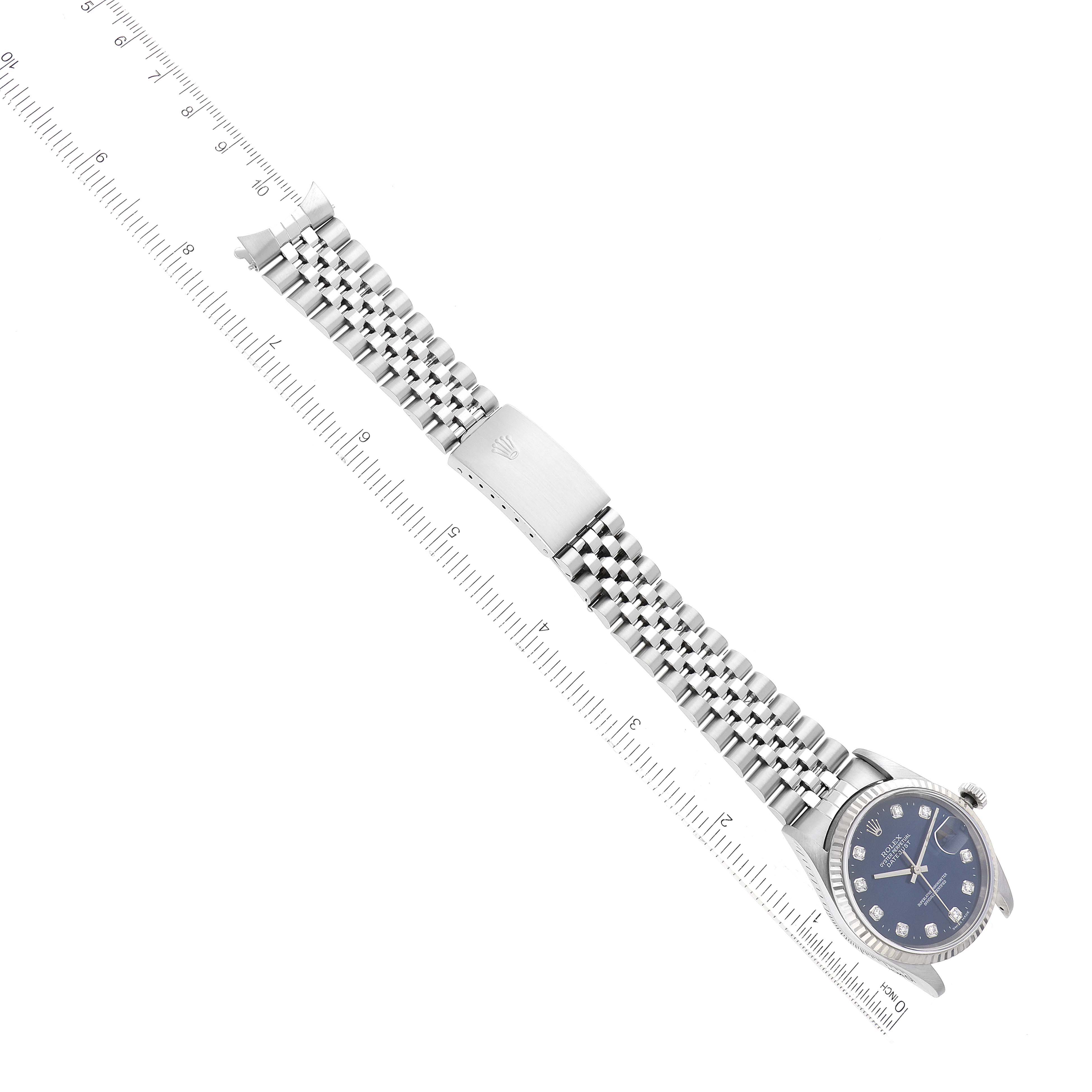 The Rolex Datejust 16234 Men's Stainless Steel Blue Dial watch is shown from a top-down angle, highlighting its bracelet, clasp, and face alongside a ruler.