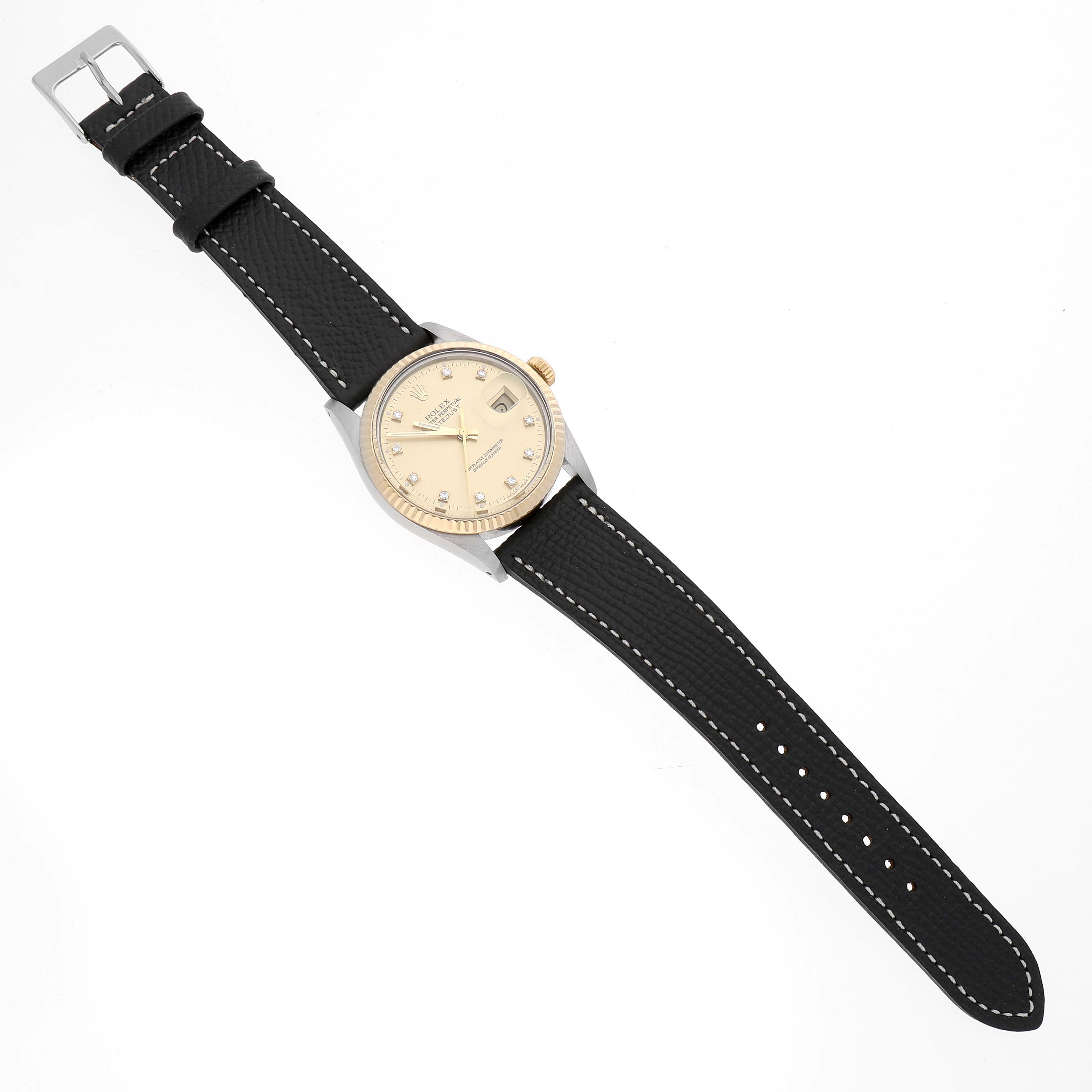The Rolex Datejust 16013 Men's Steel and Gold (two tone) Champagne Dial watch is shown from a top-down angle, featuring its cream dial, gold bezel, and black leather strap with white stitching.