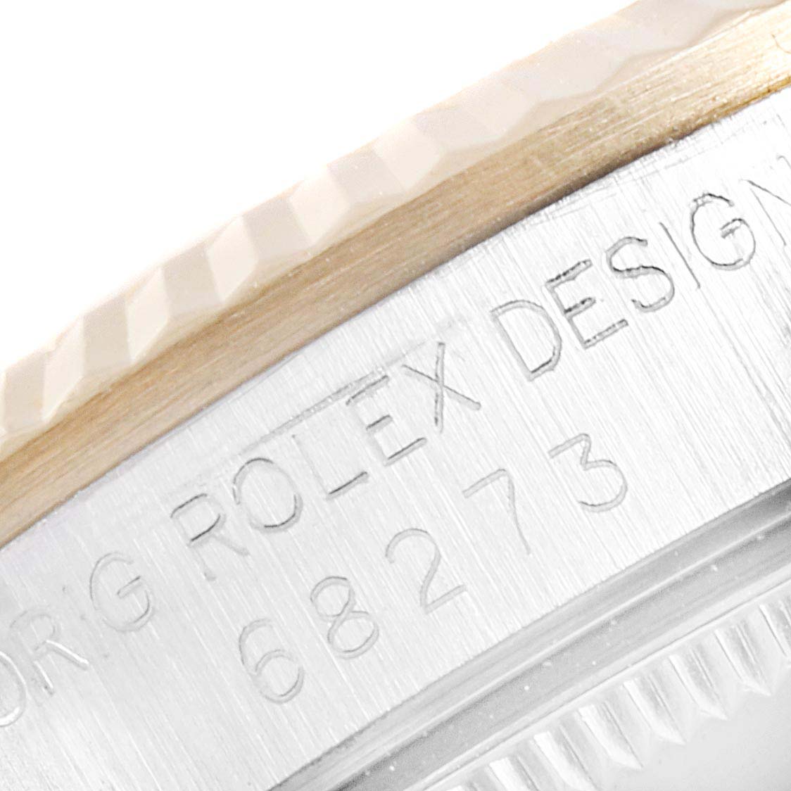 The image shows a close-up angle of the edge and part of the bezel of a Rolex Mid-Size 68273 Women
s Steel and Gold (two tone) Champagne Dial 68273 Women
s Steel and Gold (two tone) Champagne Dial model watch, displaying engravings.