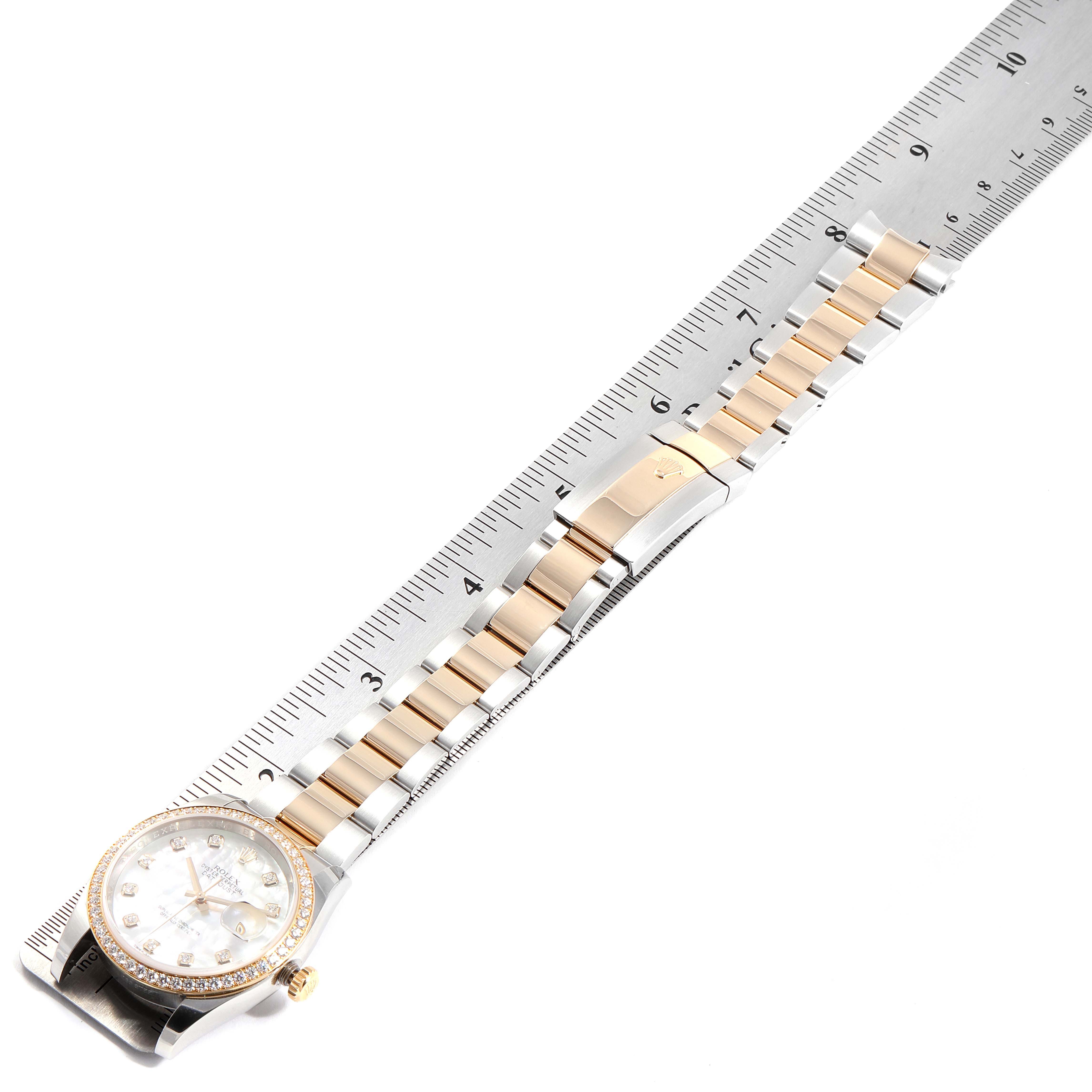 The image shows a top-down view of a Rolex Datejust 116243 Men
s Steel and Gold (two tone) Mother of Pearl Dial 116243 Men
s Steel and Gold (two tone) Mother of Pearl Dial watch, including the face, bezel, and bracelet, with a ruler for scale.