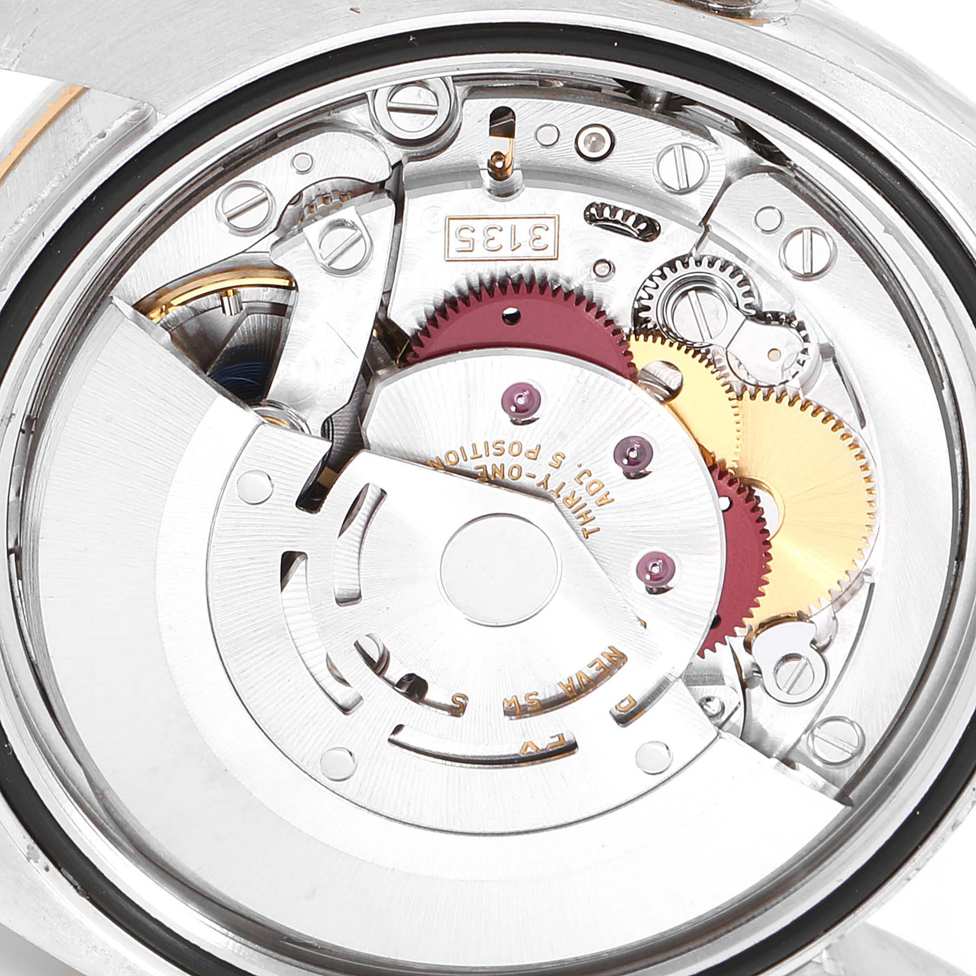 The image shows the internal movement and gears of the Rolex Datejust 116243 Men
s Steel and Gold (two tone) Mother of Pearl Dial 116243 Men
s Steel and Gold (two tone) Mother of Pearl Dial watch from a close-up back angle.
