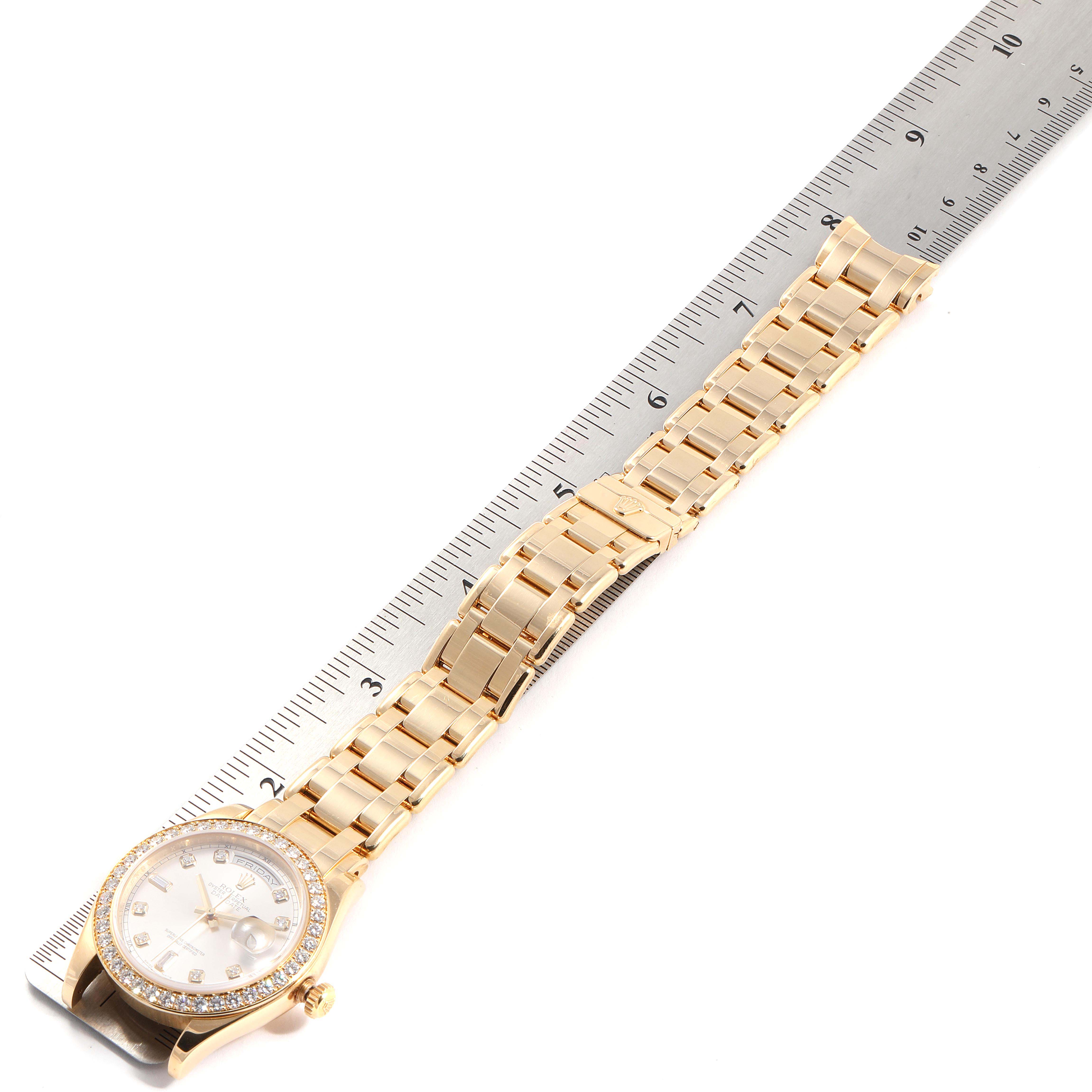 This image shows a Rolex President  Men
s Yellow Gold Silver Dial  Men
s Yellow Gold Silver Dial model watch laid next to a ruler, displaying the face and wristband at an oblique angle.