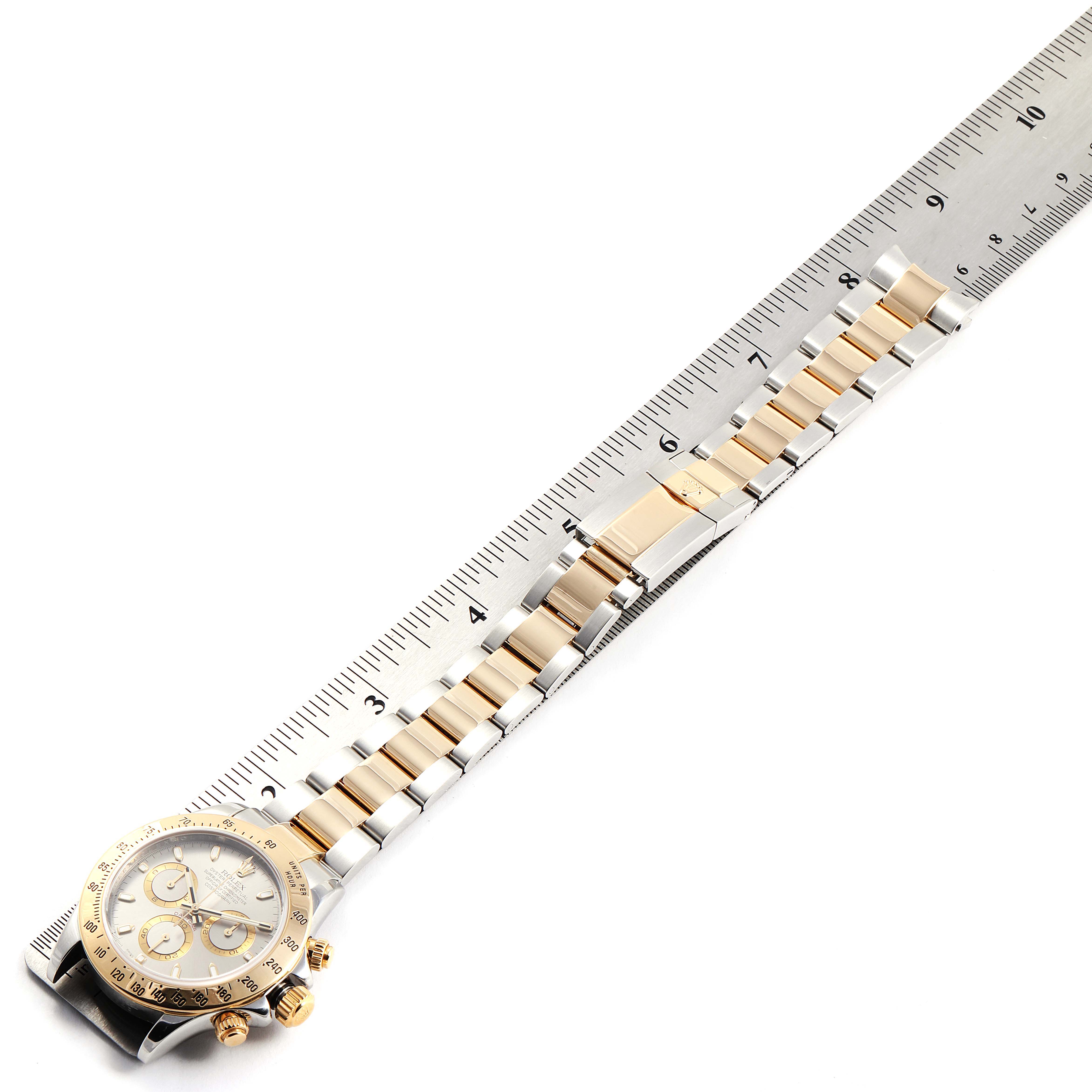 The image shows a Rolex Daytona 116523 Men's Steel and Gold (two tone) Grey Dial 116523 Men's Steel and Gold (two tone) Grey Dial watch, taken at an angle displaying both the face and the band, with a ruler measuring the length.