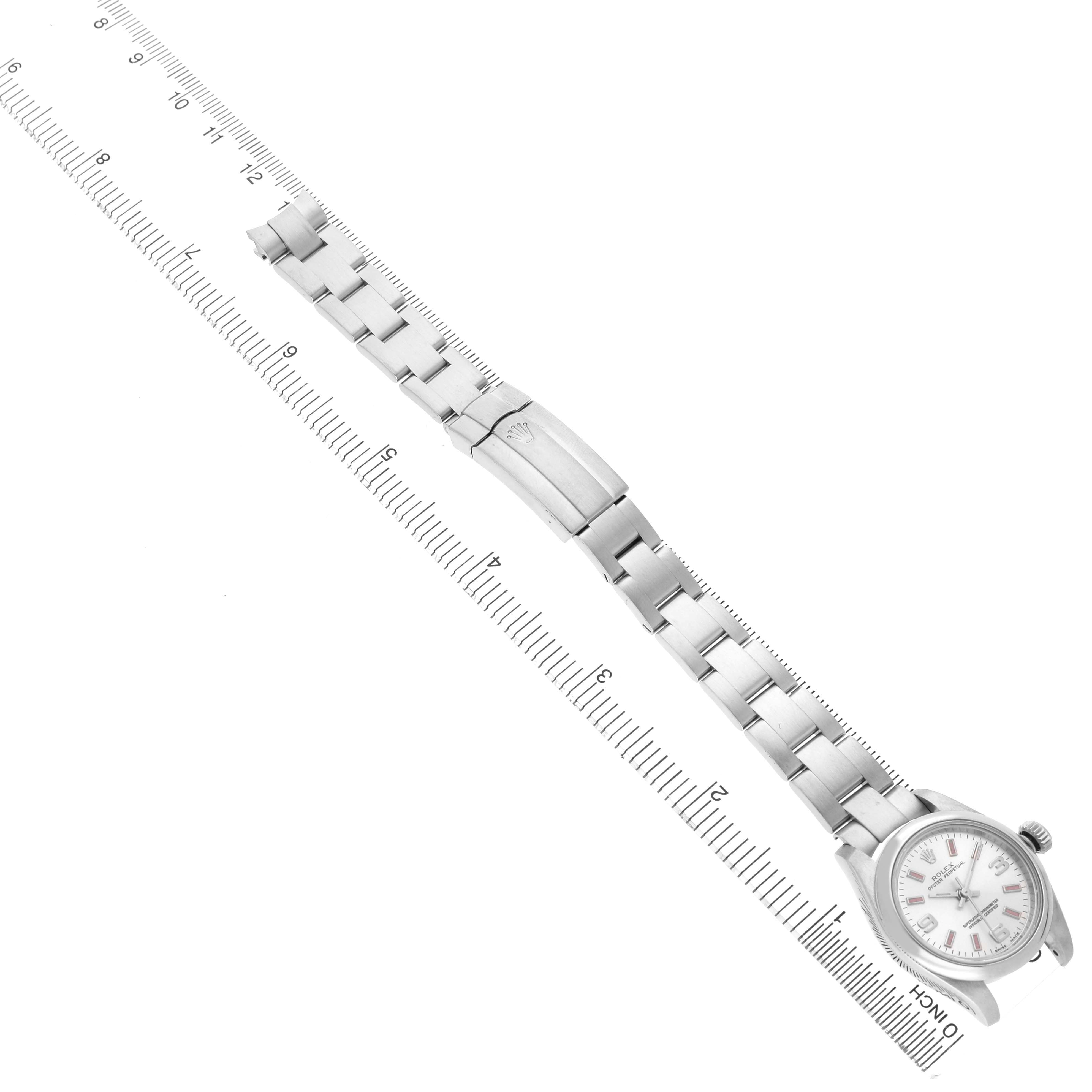 The Rolex Oyster Perpetual 176200 Women's Stainless Steel Silver Dial watch is shown from a top-down angle, featuring its full bracelet and clasp against a measuring ruler.
