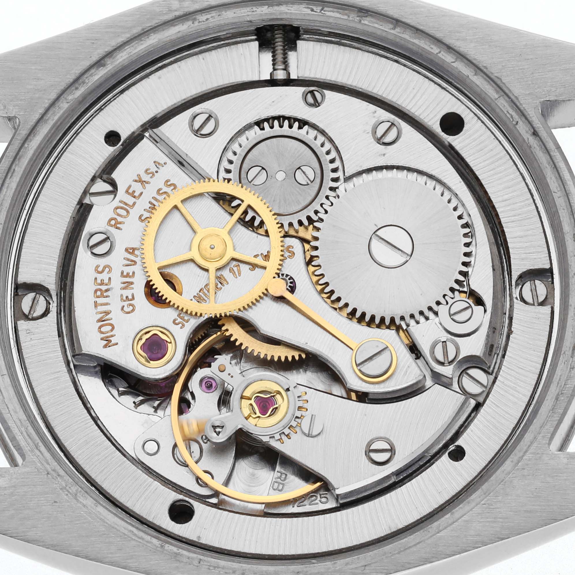 The image shows the internal mechanism of a Rolex Date watch, highlighting gears, springs, and precision components from a top-down view.