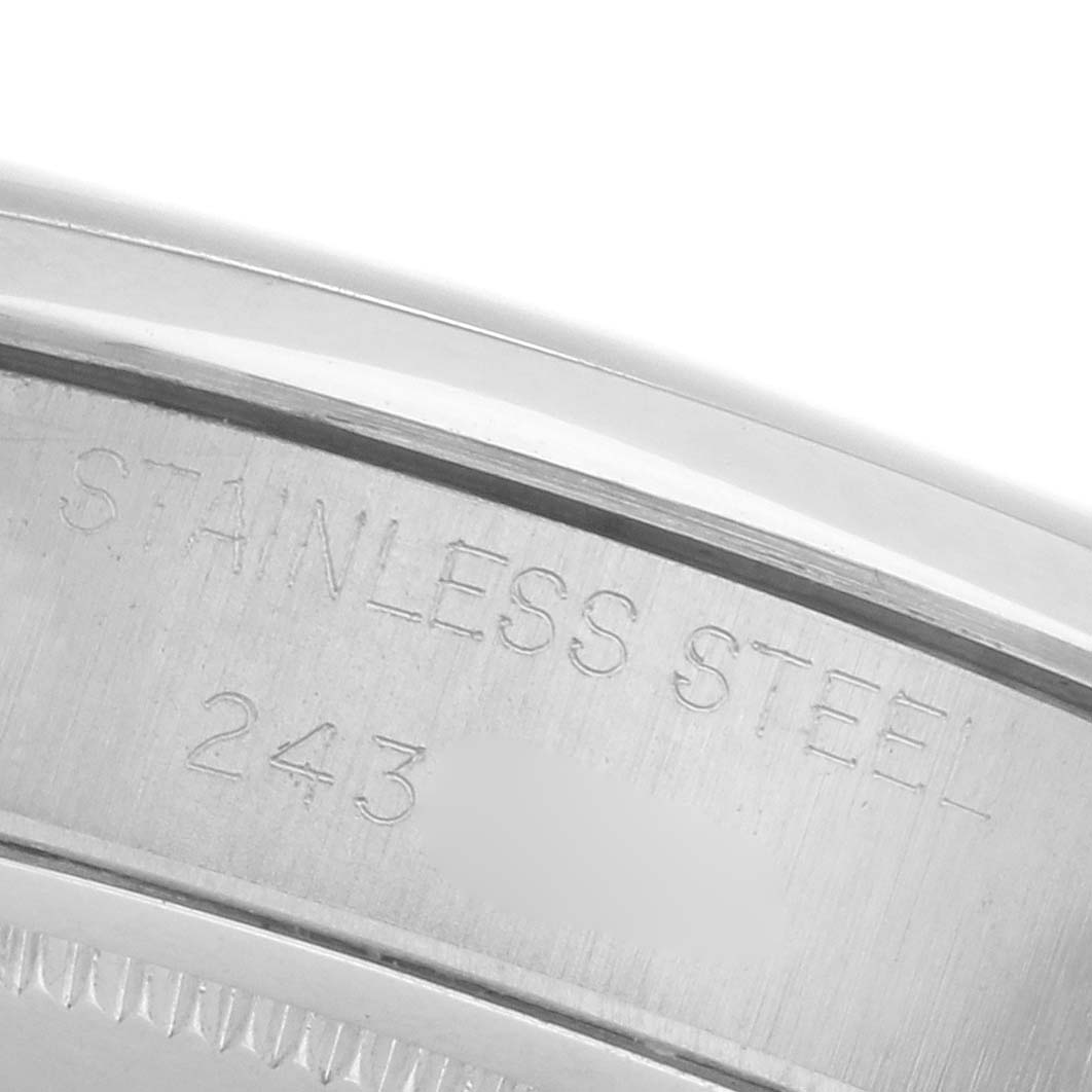 The image shows a close-up of the Rolex Date's case back, highlighting "STAINLESS STEEL" engraving.