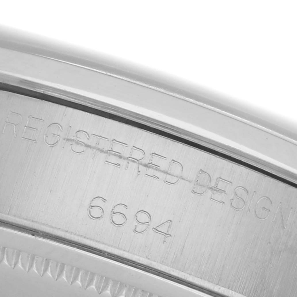 The image shows a close-up of the case back edge with engraved markings on the Rolex Date model watch.