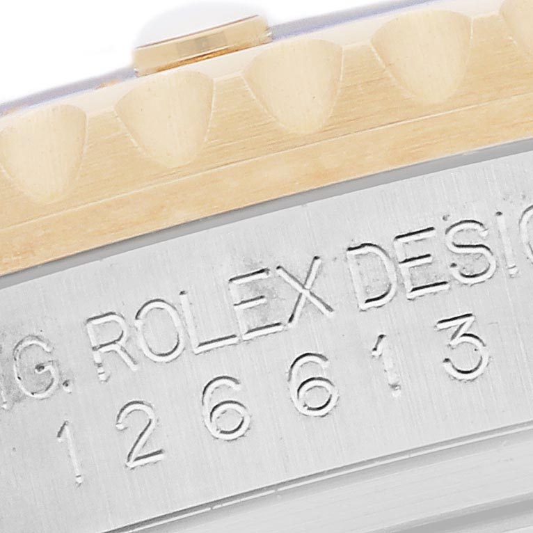 The image shows a close-up angle of the side of a Rolex Submariner 126613 Men's Steel and Gold (two tone) Blue Dial 126613 Men's Steel and Gold (two tone) Blue Dial, focusing on the engraved serial numbers and the edge of the bezel.
