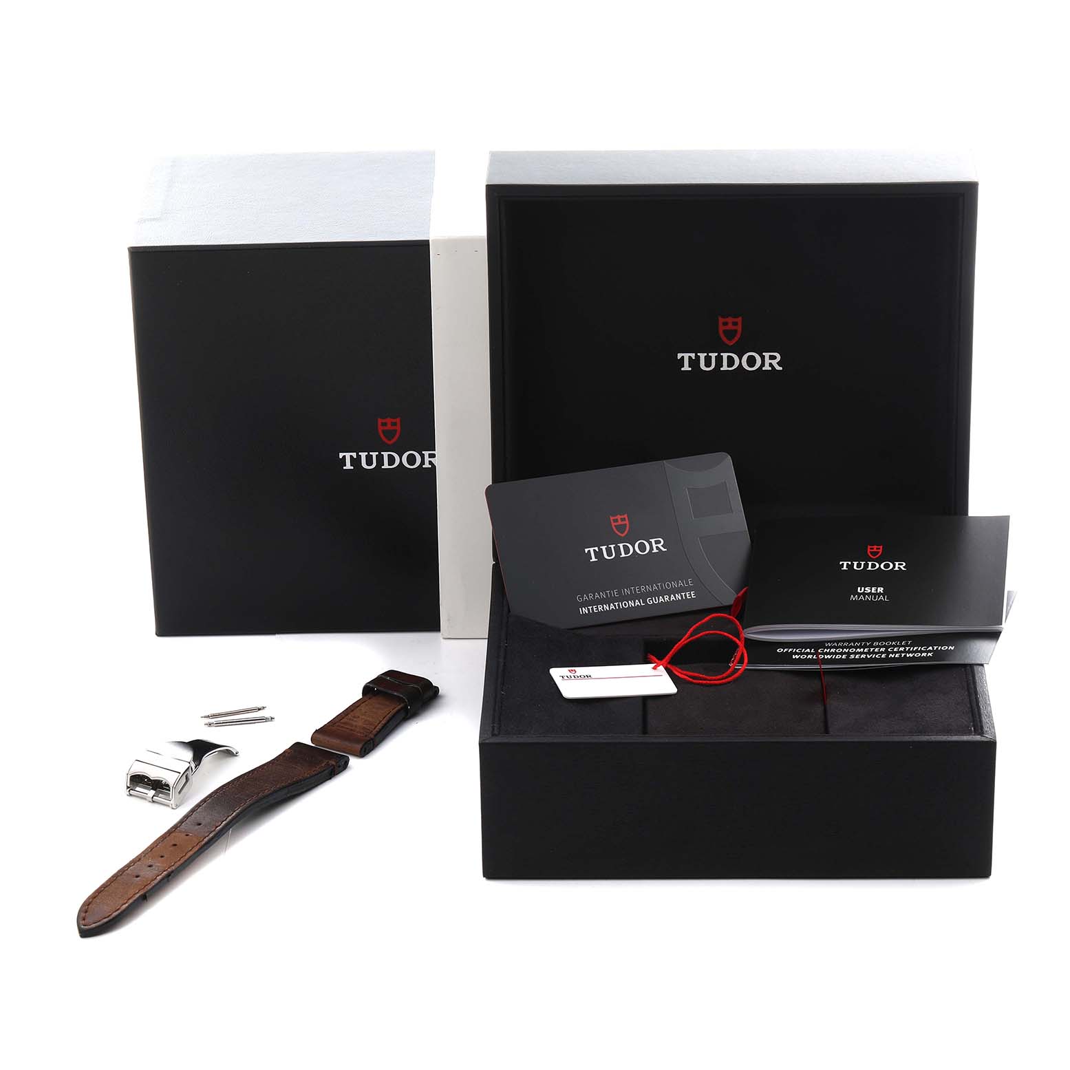 The watch, a Tudor Heritage Black Bay 79030 Men
s Stainless Steel Black Dial 79030 Men
s Stainless Steel Black Dial, is shown with its box, extra strap, buckle, and guarantee cards.