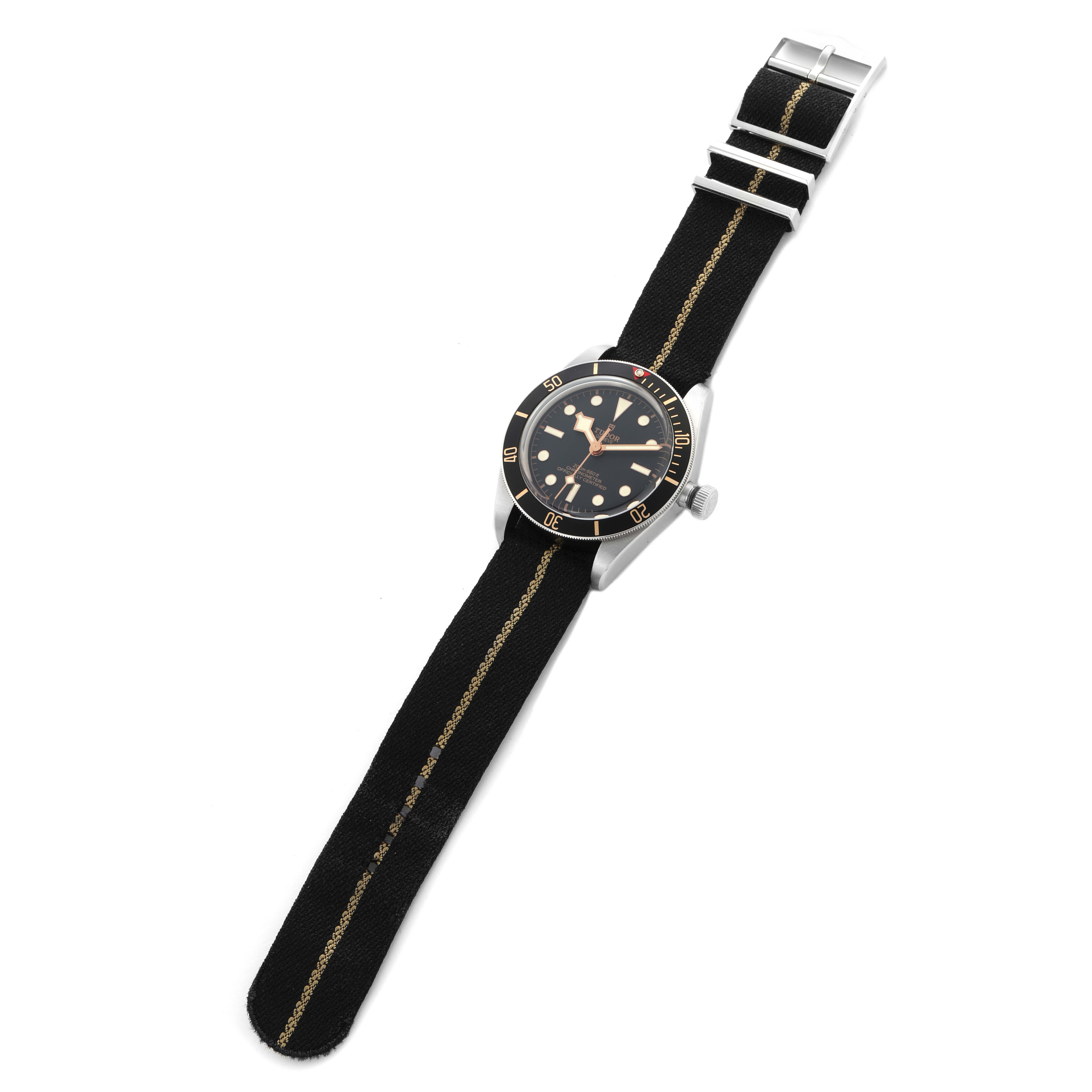 The Tudor Heritage Black Bay 79030 Men
s Stainless Steel Black Dial 79030 Men
s Stainless Steel Black Dial watch is shown from a top view, featuring the full face and black fabric strap with metal clasps.