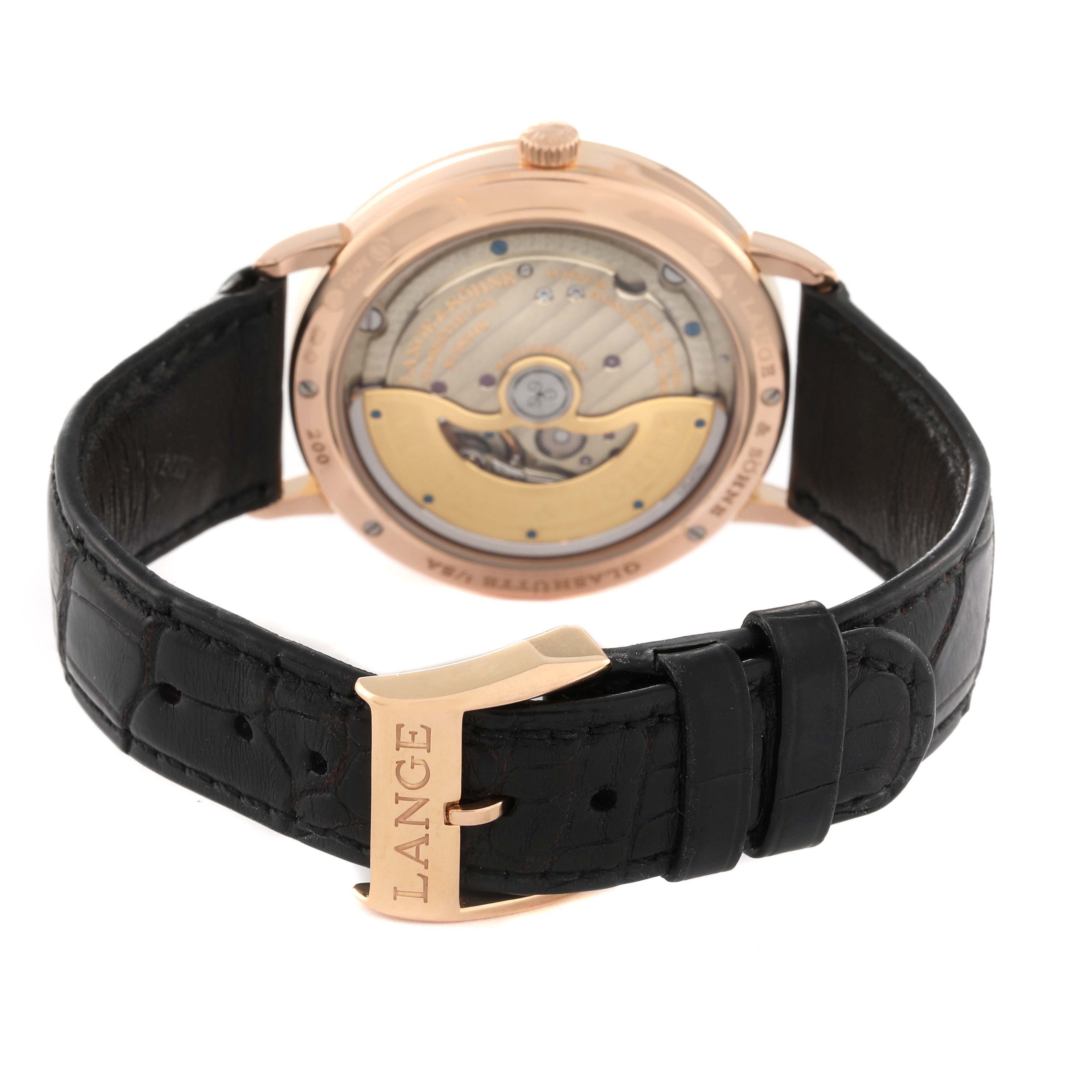 The image shows the back view of the A. Lange & Sohne Saxonia 842.032 Men's Rose Gold Silver Dial watch, highlighting its movement and leather strap with a "LANGE" engraved buckle.