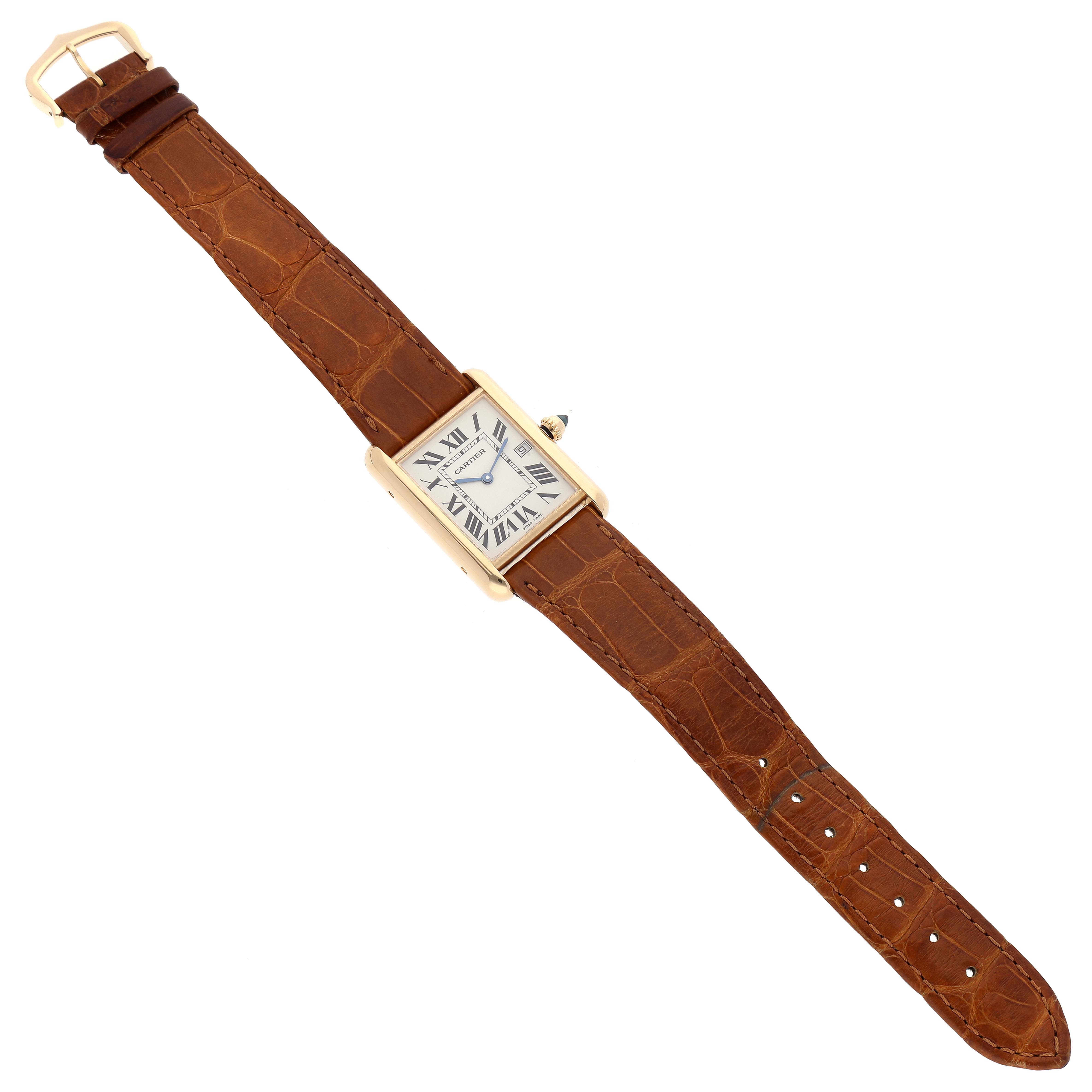 The Tank Louis watch by Cartier is shown from above, displaying its beige leather strap and rectangular face with Roman numerals.