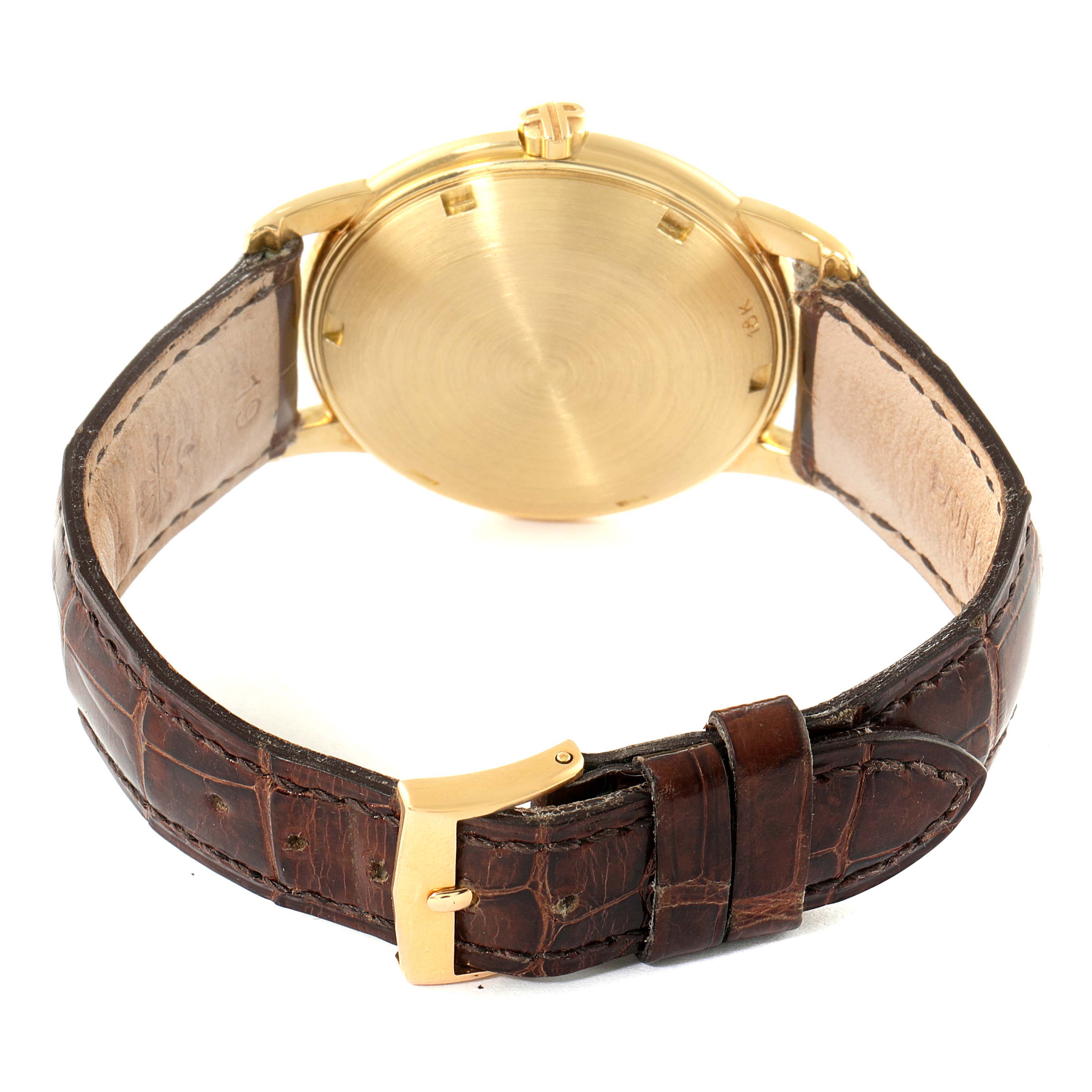 The image shows the back side of a Patek Philippe Calatrava 2551J Men's Yellow Gold Silver Dial 2551J Men's Yellow Gold Silver Dial watch, detailing its gold case and brown leather strap with a gold buckle.