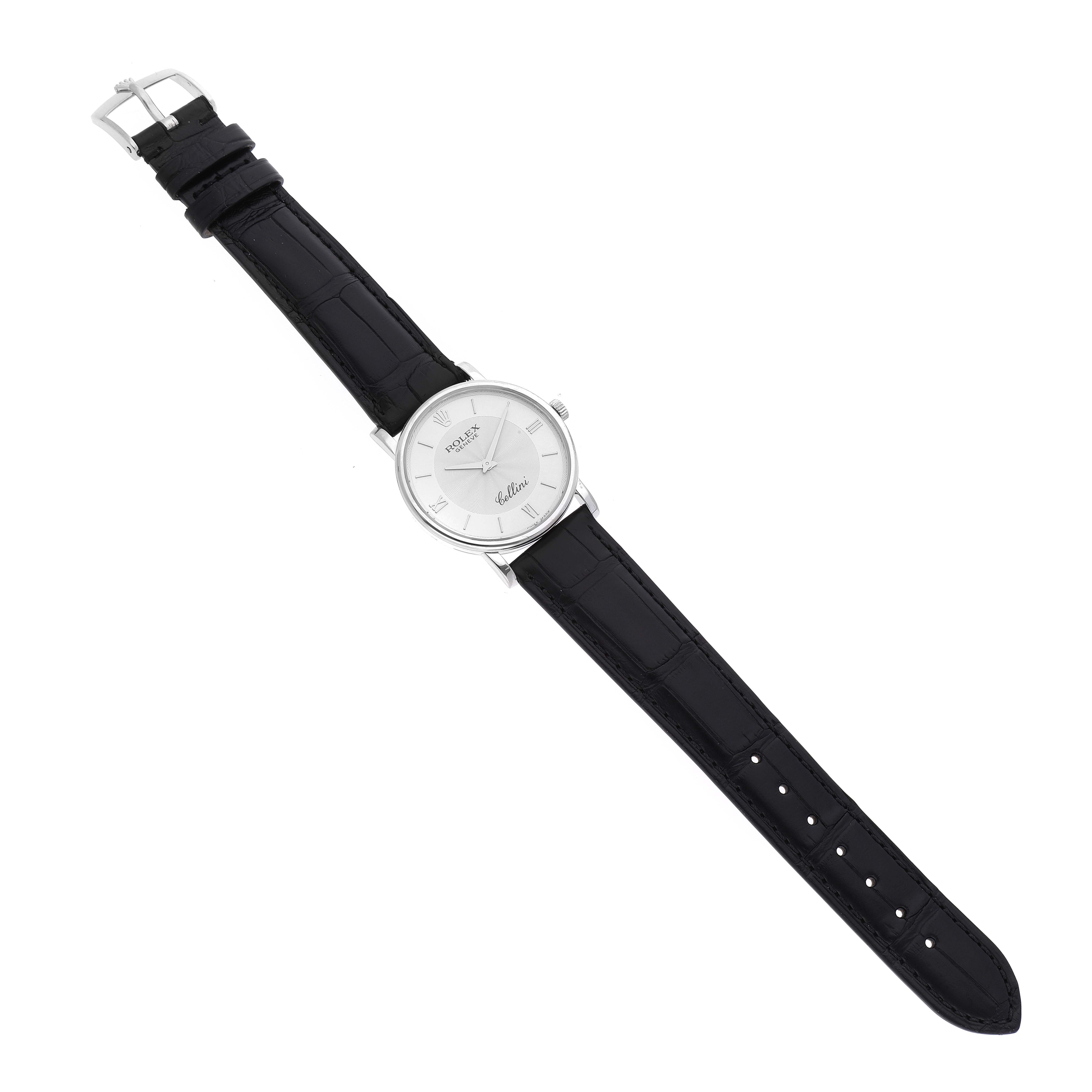 The image shows a top-down view of a Rolex Cellini 5115 Men's White Gold Silver Dial 5115 Men's White Gold Silver Dial watch, featuring its black leather strap and silver watch face.