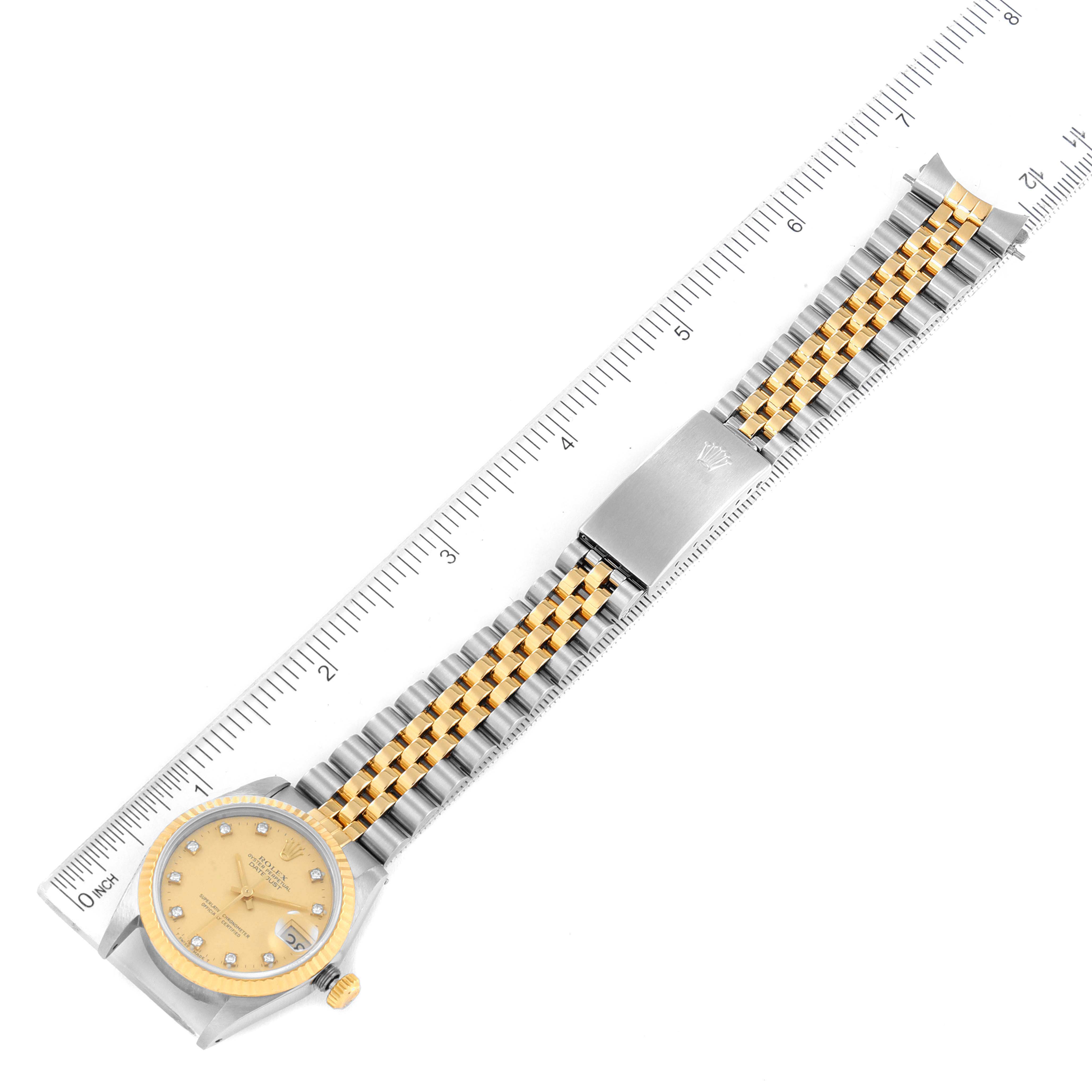 The image shows a Rolex Mid-Size 68273 Women
s Steel and Gold (two tone) Champagne Dial 68273 Women
s Steel and Gold (two tone) Champagne Dial watch laid flat with its gold and silver bracelet positioned next to a ruler for scale.