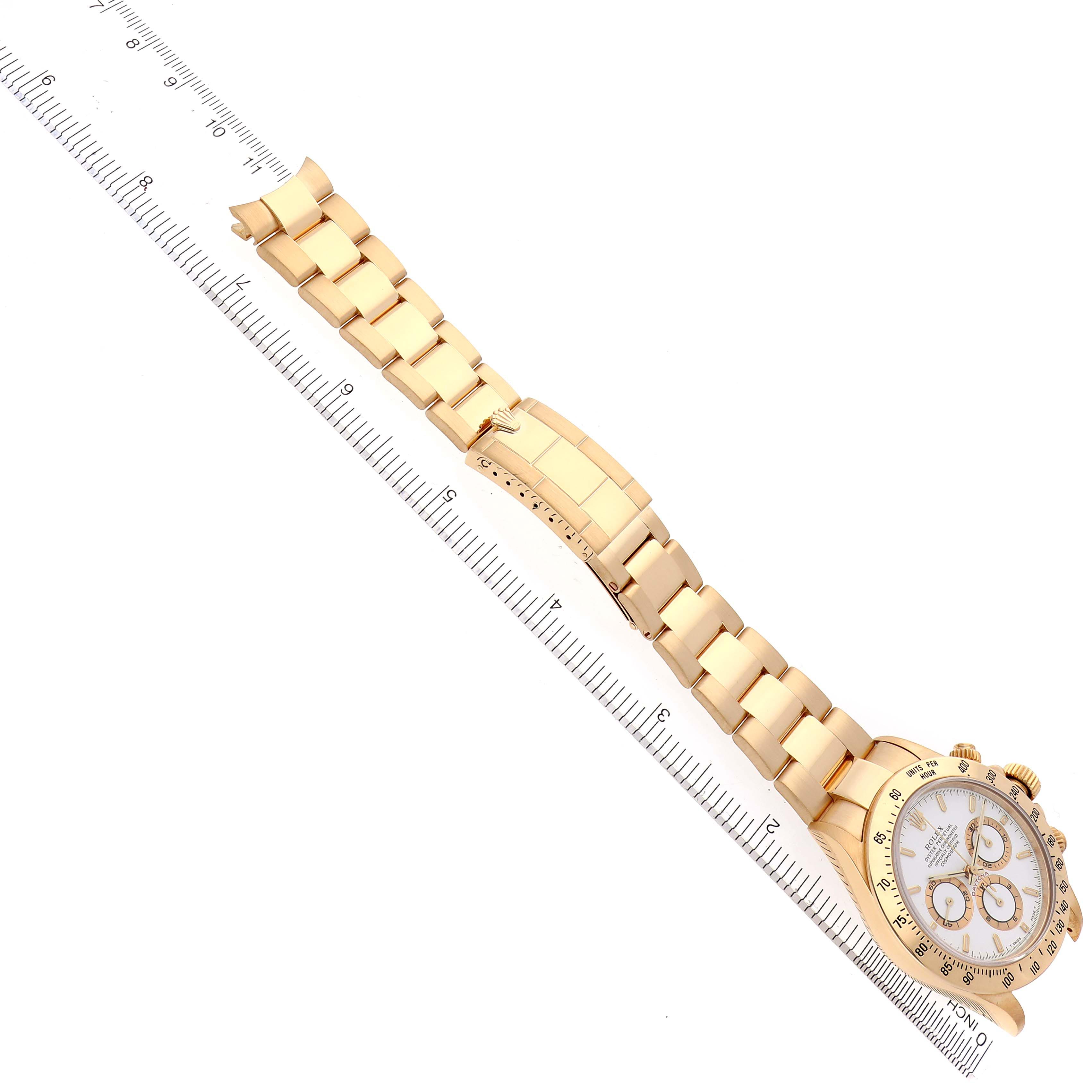 The Rolex Daytona 16528 Men's Yellow Gold White Dial 16528 Men's Yellow Gold White Dial watch is shown from an overhead angle, displaying the full bracelet and face alongside a ruler for scale.