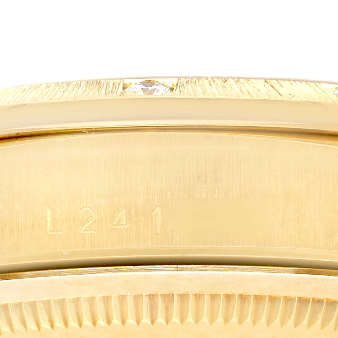 This image shows a close-up of the side of a Rolex President 18308 Men's Yellow Gold Black Dial 18308 Men's Yellow Gold Black Dial model watch, highlighting its engraved serial number and part of the bezel with diamonds.