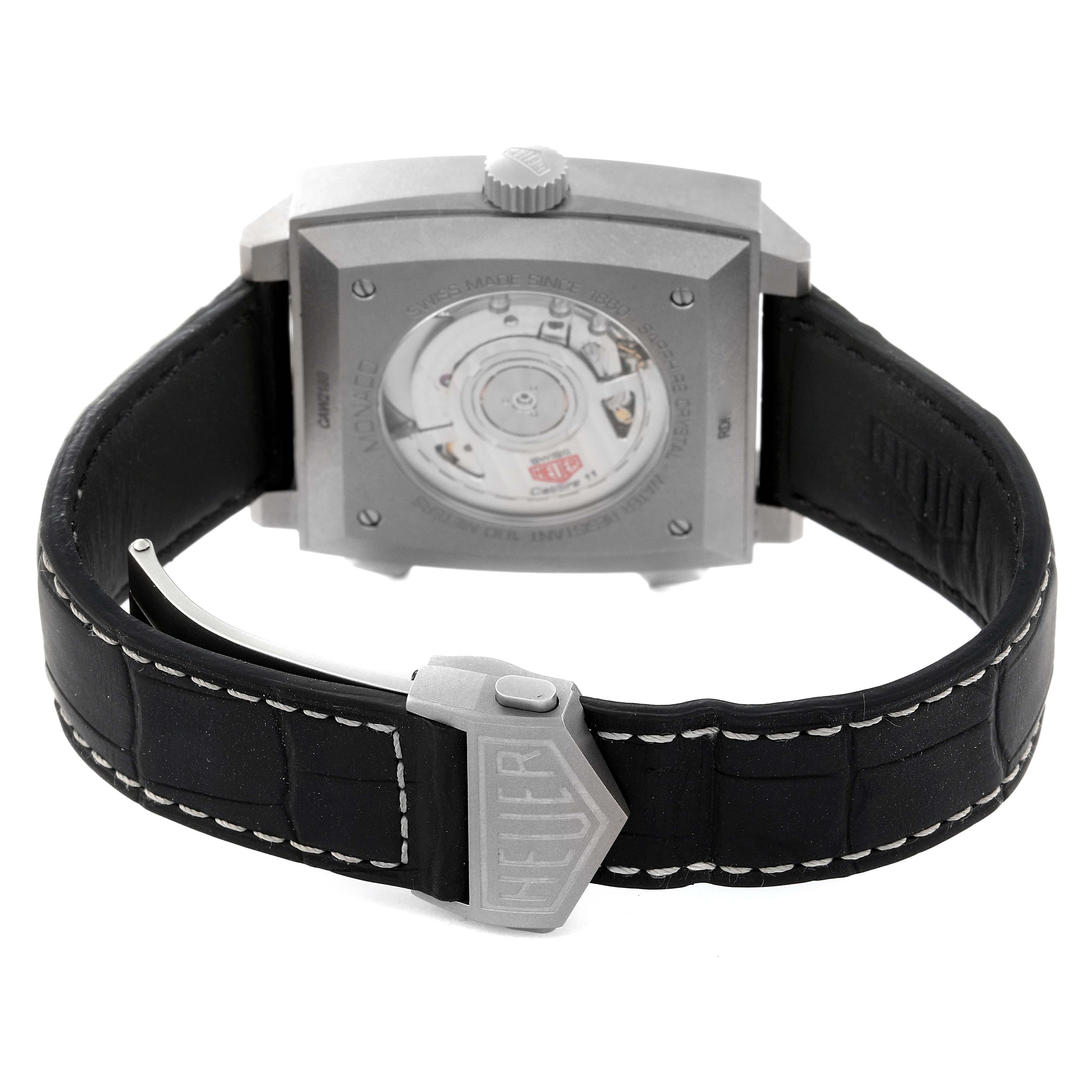 The image shows the back view of the Tag Heuer Monaco CAW218B.FC6496 Men's Titanium Silver Dial CAW218B.FC6496 Men's Titanium Silver Dial model watch, including its movement and leather strap with buckle.
