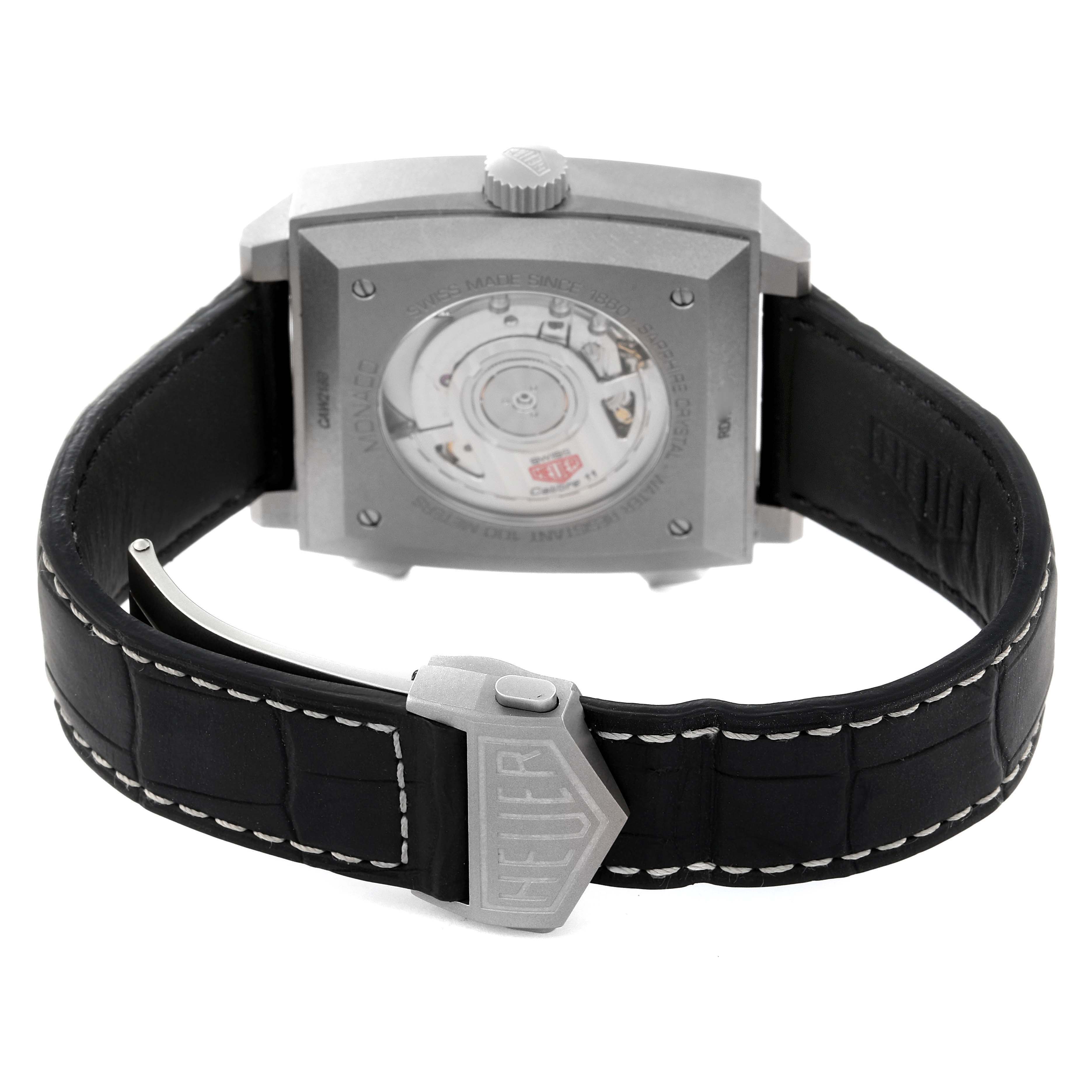 The image shows the back of a Tag Heuer Monaco CAW218B.FC6496 Men's Titanium Silver Dial, highlighting its case back, movement, and strap with a deployment clasp.