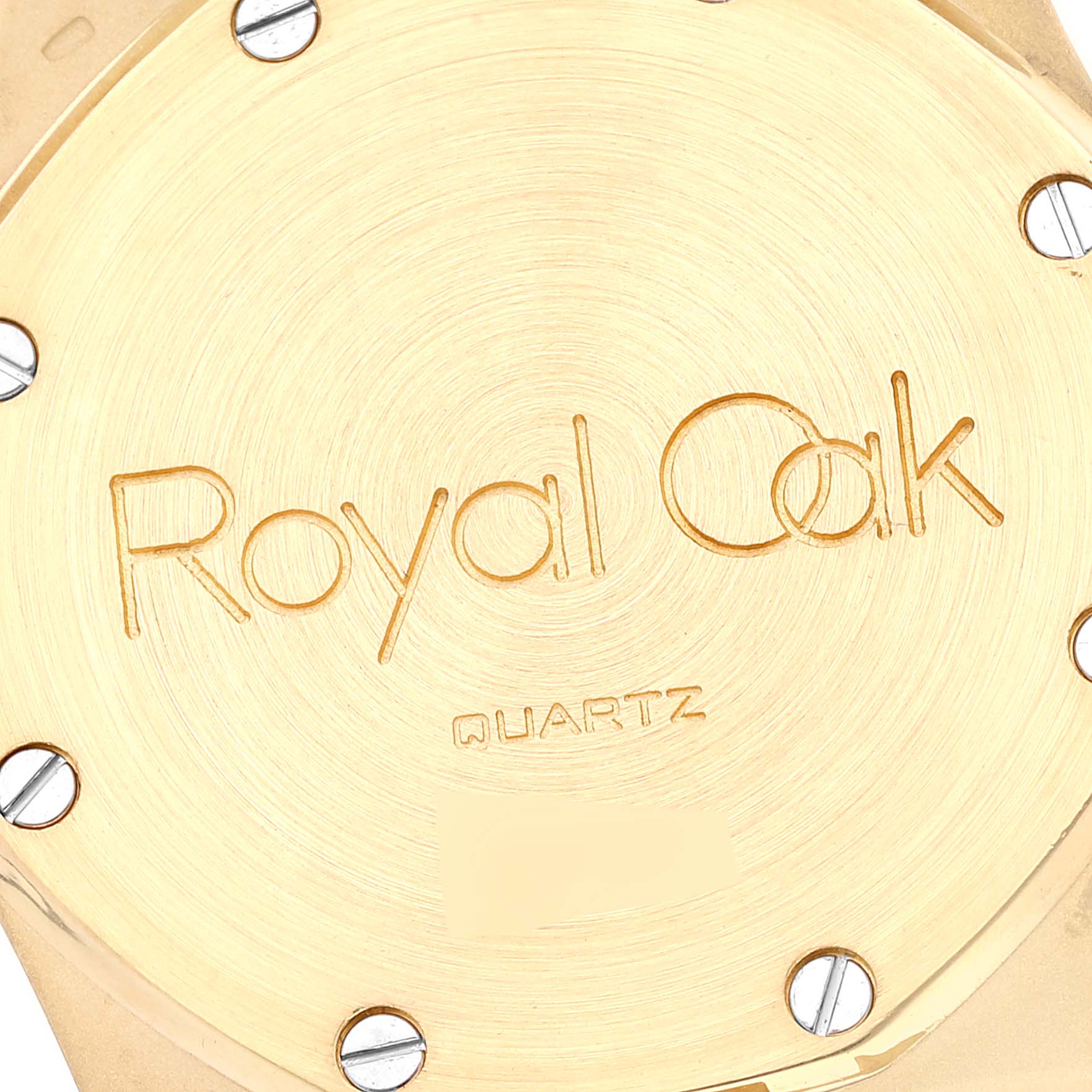 This is a close-up of the case back of the Audemars Piguet Royal Oak Men's Yellow Gold Champagne Dial Men's Yellow Gold Champagne Dial Quartz model, showing its engraved text and screws.