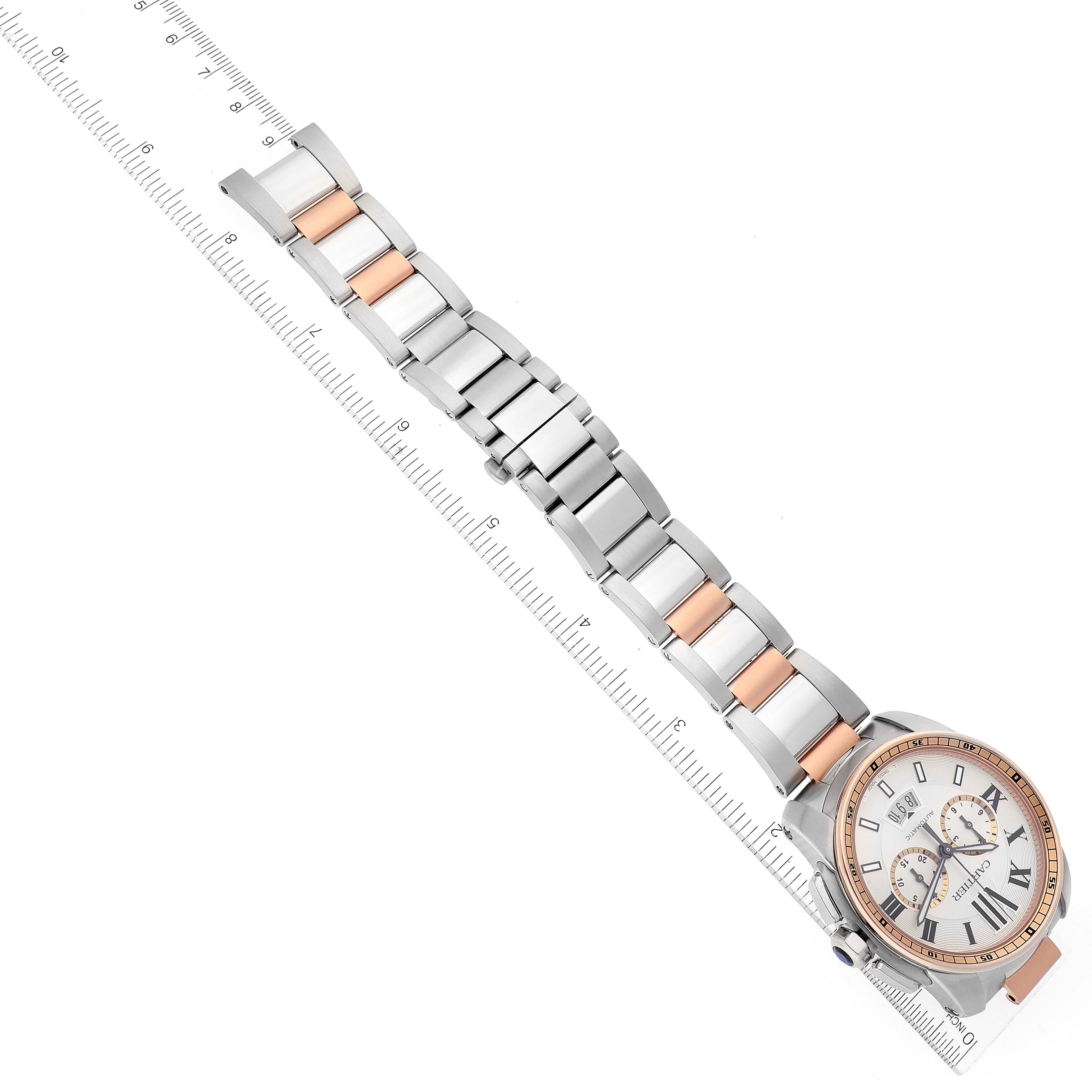 The image shows a Calibre de Cartier watch by Cartier angled diagonally, illustrating the face and the two-tone metal bracelet alongside a ruler.