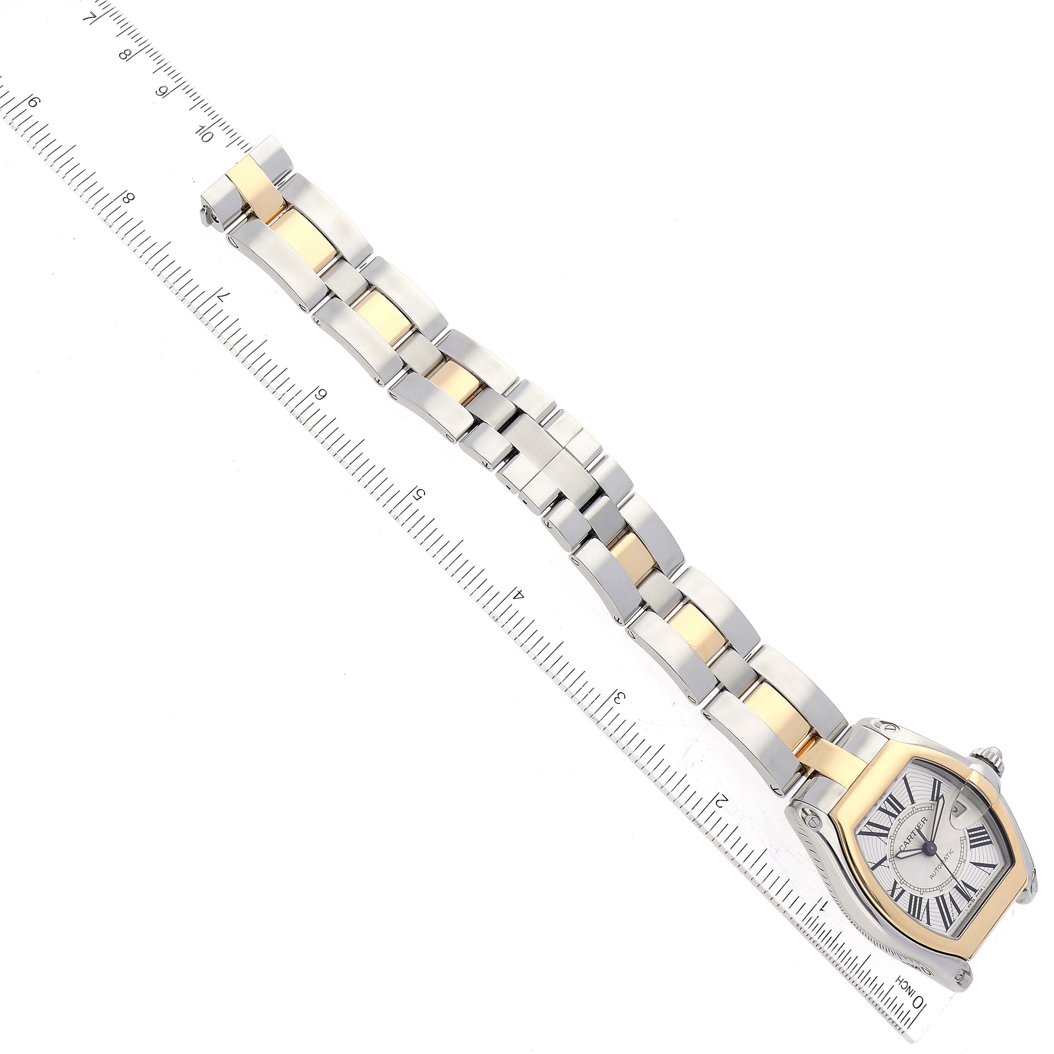 This image shows a top view of a Cartier Roadster W62031Y4 Men's Steel and Gold (two tone) Silver Dial W62031Y4 Men's Steel and Gold (two tone) Silver Dial watch with its metal and gold bracelet extended alongside a ruler.