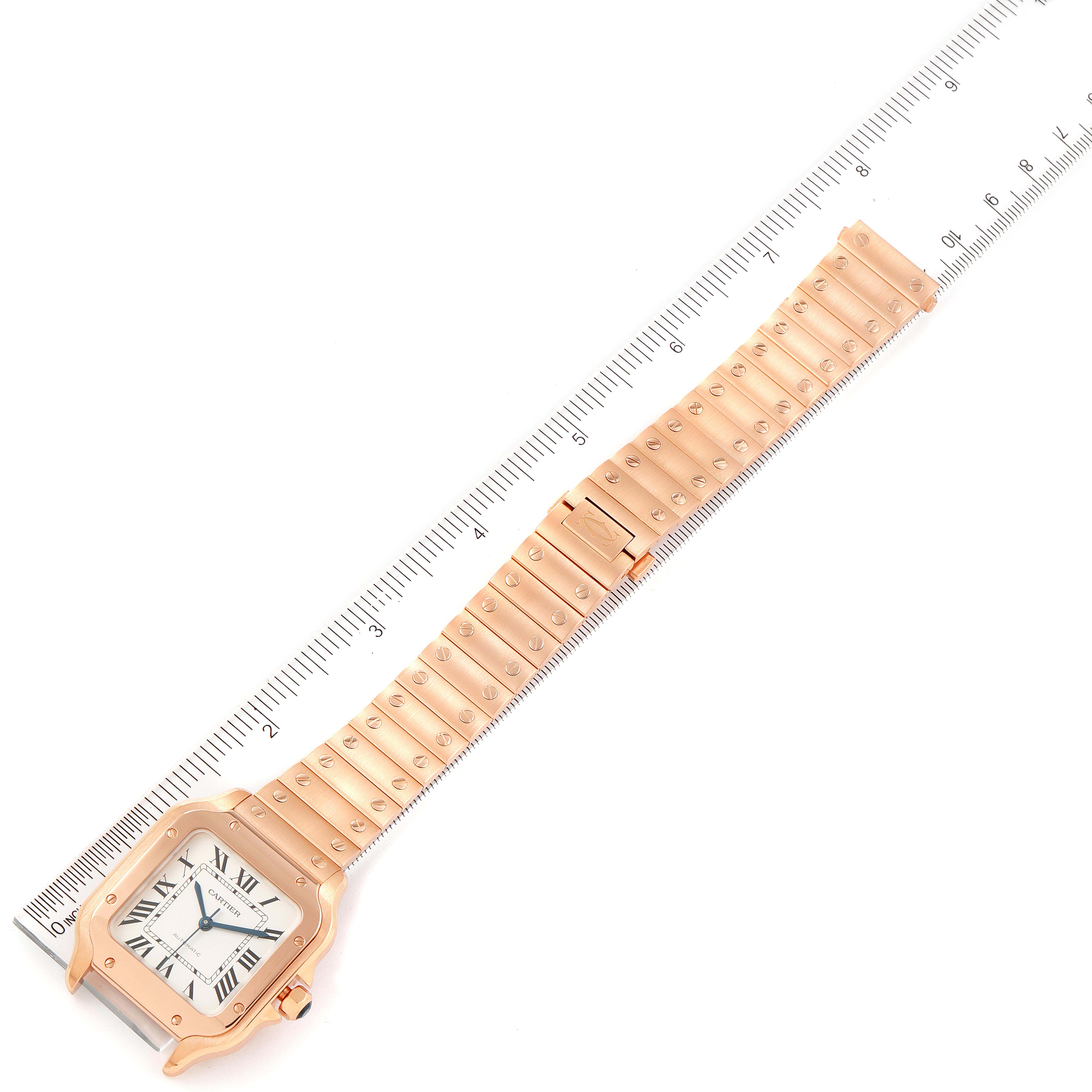 The image shows a Cartier Santos WGSA0008 Men's Rose Gold Silver Dial WGSA0008 Men's Rose Gold Silver Dial watch laid flat, with a golden face and bracelet, placed against a measuring ruler.