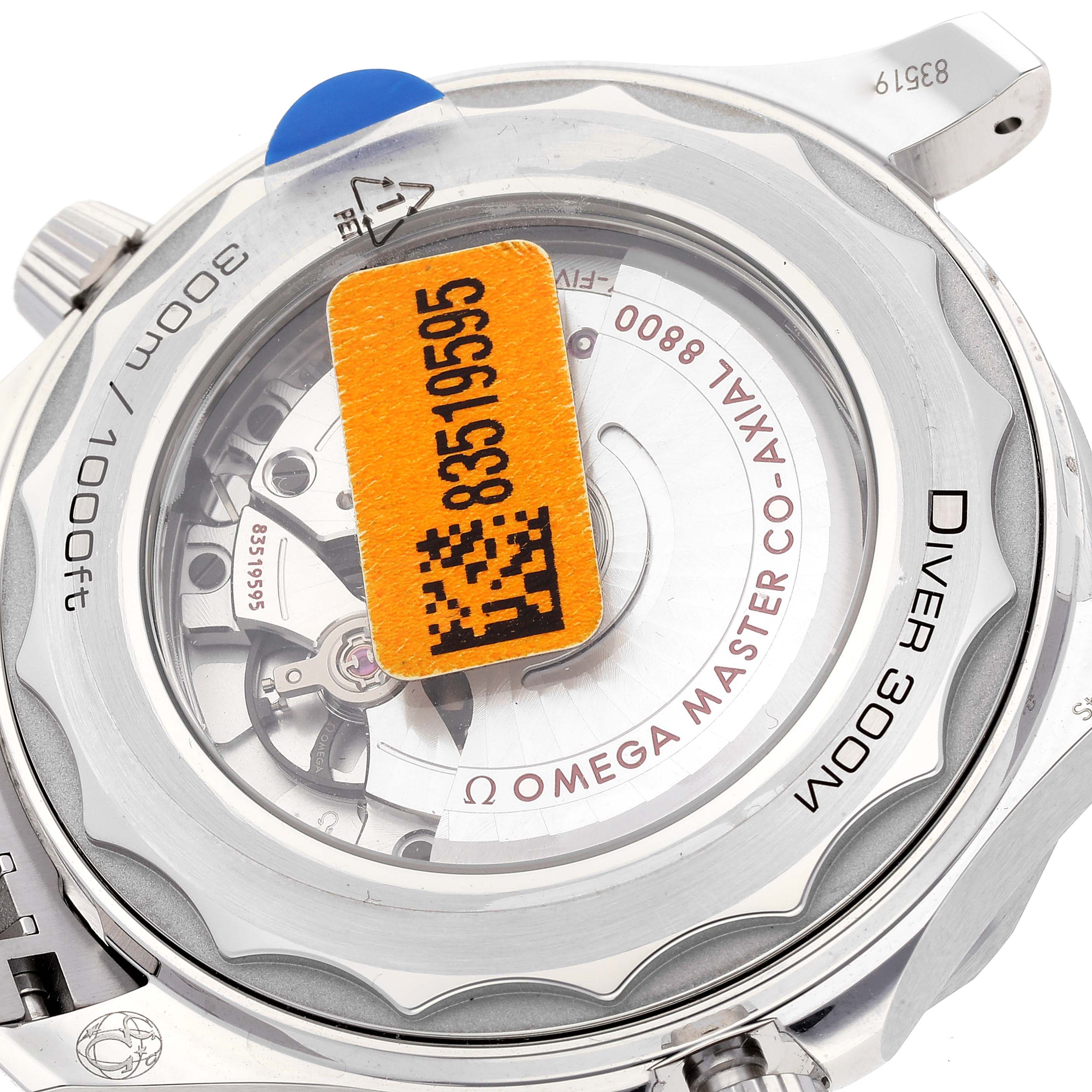 The image shows the back of an Omega Seamaster 210.30.42.20.03.001 Men's Stainless Steel Blue Dial 210.30.42.20.03.001 Men's Stainless Steel Blue Dial Diver 300M watch, revealing its internal mechanism with a sticker covering part of it.