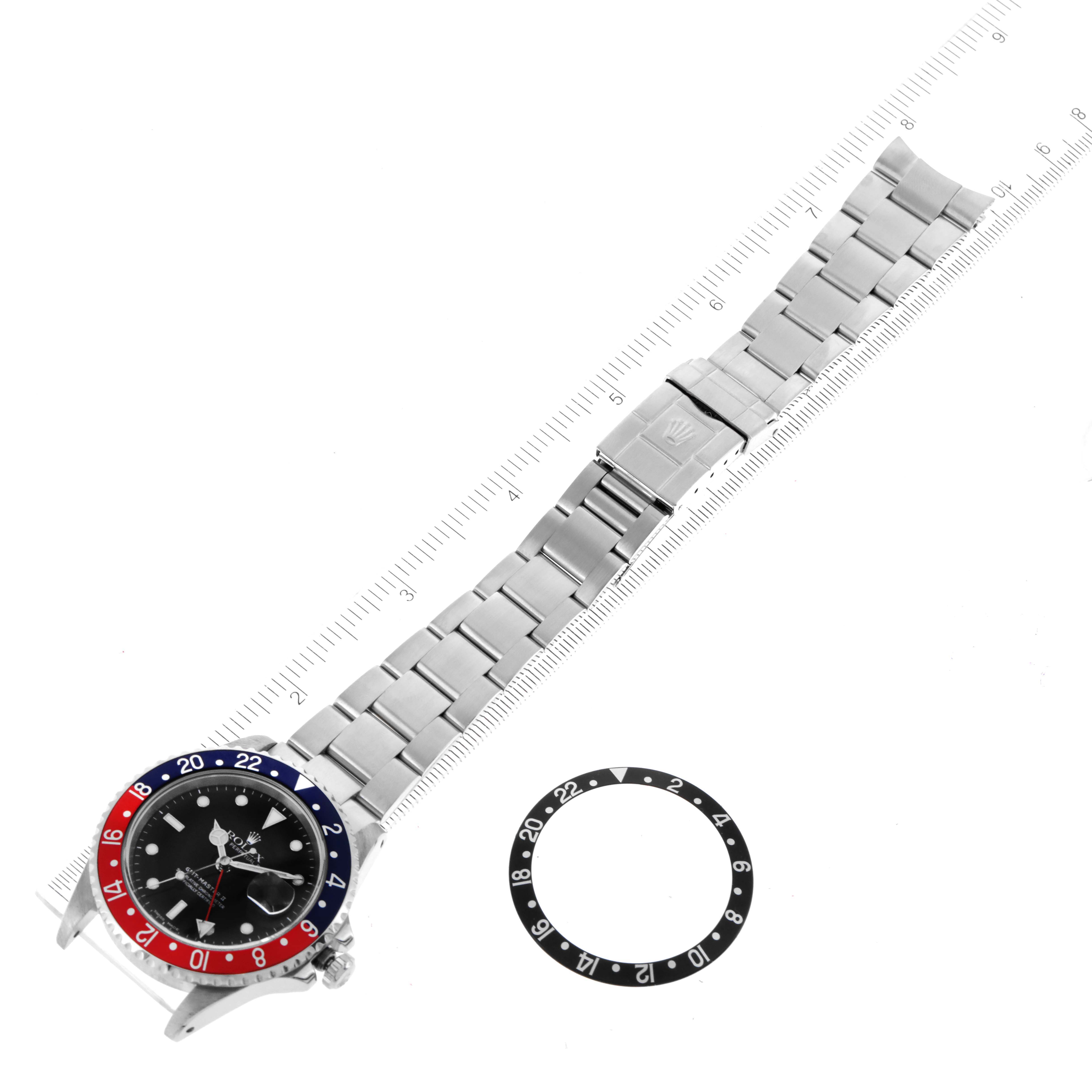 The image shows a Rolex GMT-Master 16710 Men
s Stainless Steel Black Dial 16710 Men
s Stainless Steel Black Dial watch laid flat with its bracelet extended and beside it, an additional bezel.